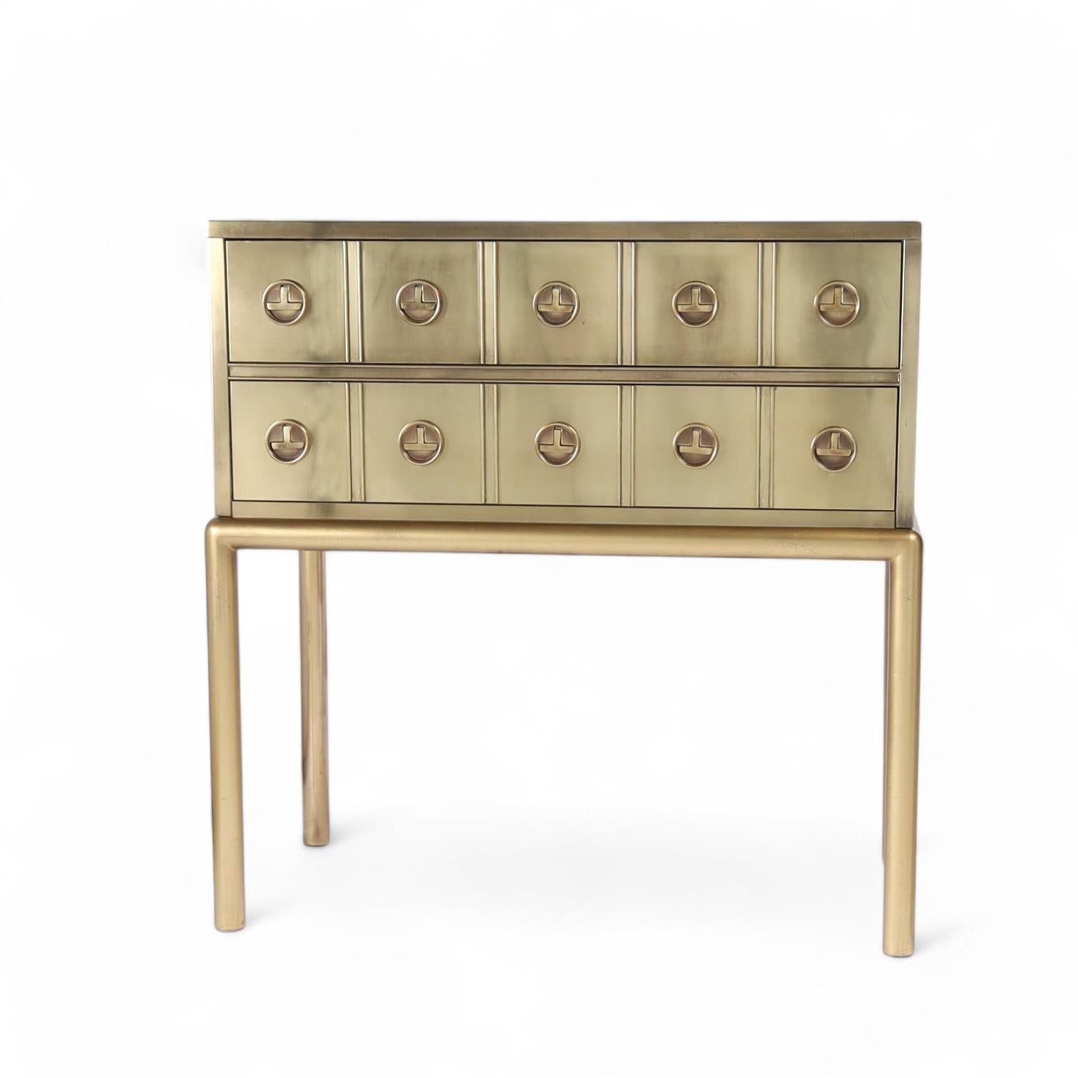 Chic pair of vintage two drawer chests on stands having a stylized modern campaign form and drawer pulls on sleek tubular legs, all with a hip custom finish. Signed Mastercraft in a drawer. 