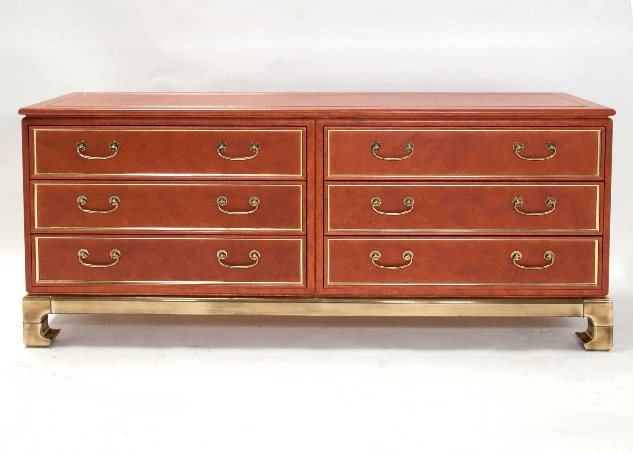 A rare six-drawer dresser attributed to Mastercraft. Faux leather paint finish, with brass detailing, inlay and handles, on a well sculpted Asian influenced base with Hollywood Regency style.