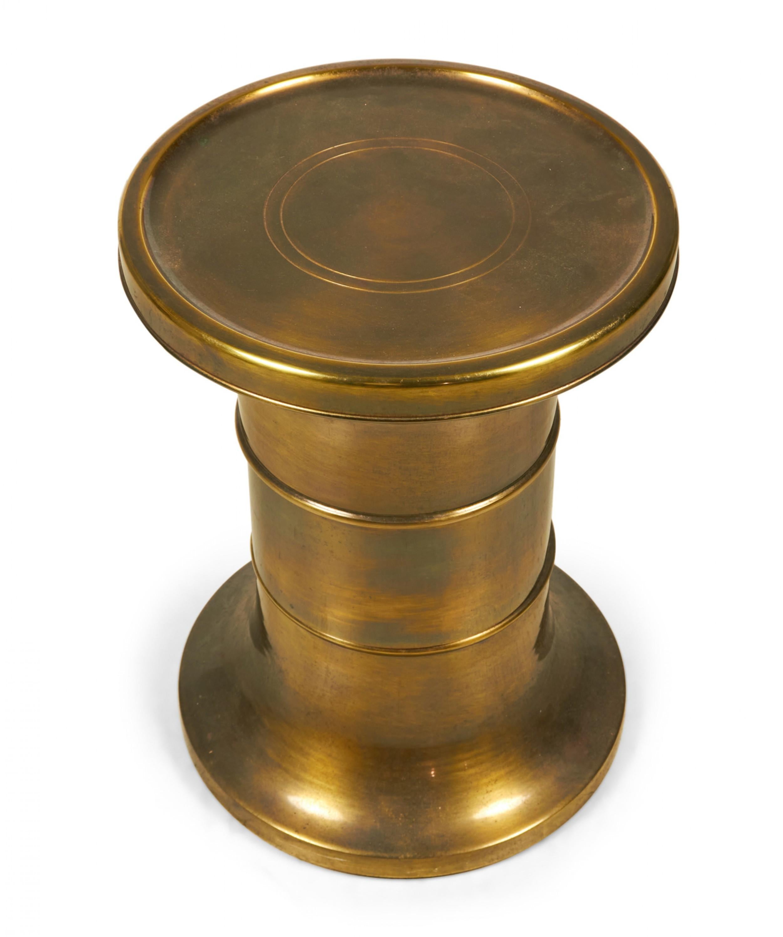 American mid-century (1970s) drum-style brass pedestal / side table with a flared top and bottom and two decorative ridges around the post and a lacquered finish. (Mastercraft / William Doezema).