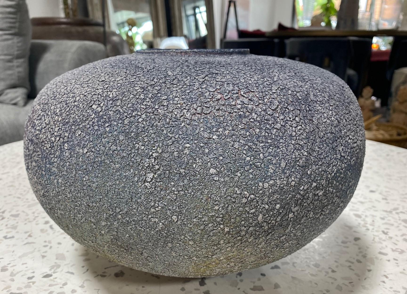 Magnifique vase en céramique cuite au feu de bois du maître potier américano-japonais Masuo Ojima.  La texture et les changements de couleur, des gris argentés aux bleus, cuivres et or, sont étonnants.  

Le vase est signé sur la base par Ojima et