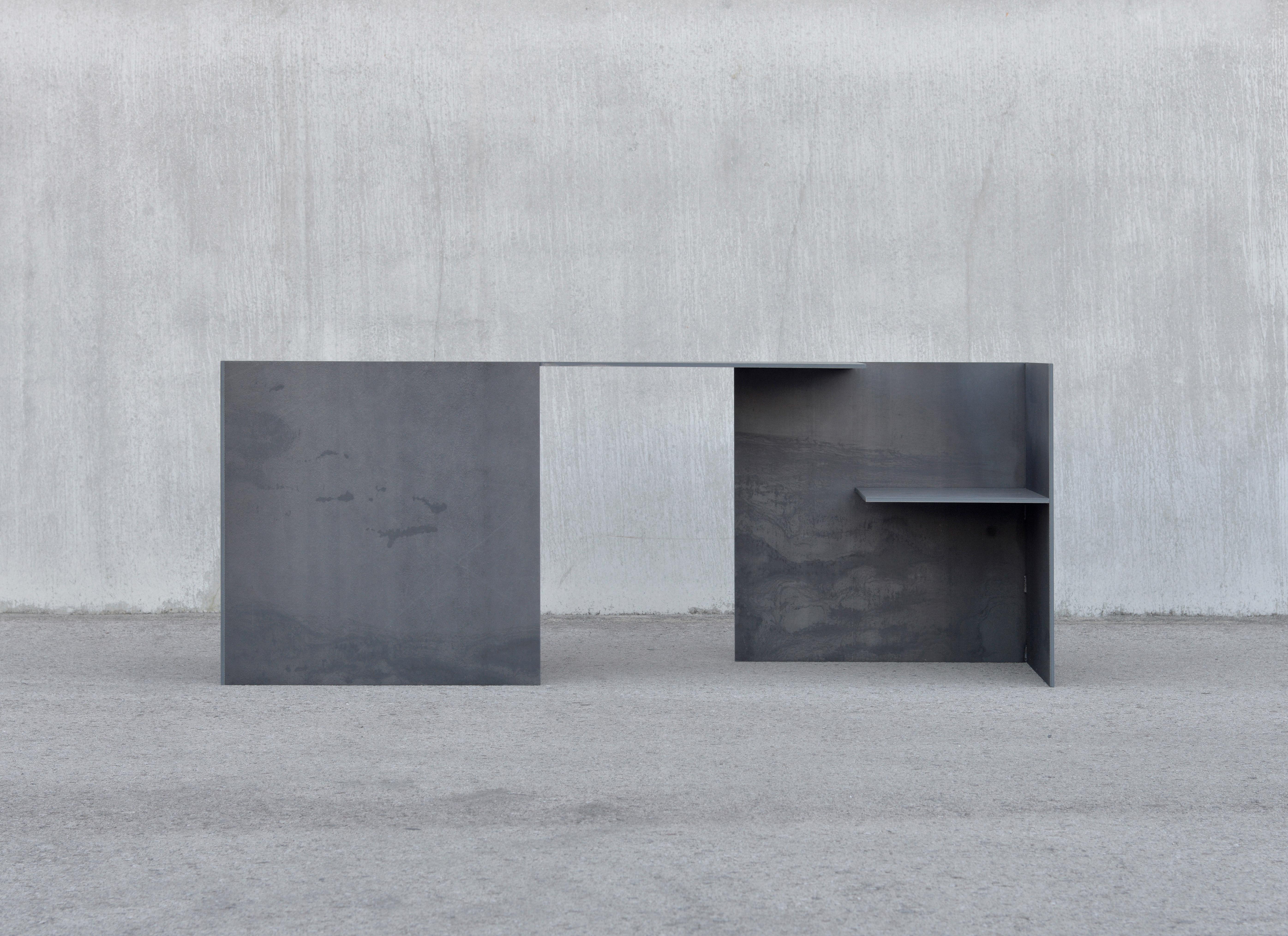 The MSB double desk 302.2 is a work comprised of 7 pieces of 10mm oxidized steel plates. A study in constructive essentialism and materialization, the designer stands in front of the assembly of large steel slats, sifting through the options with