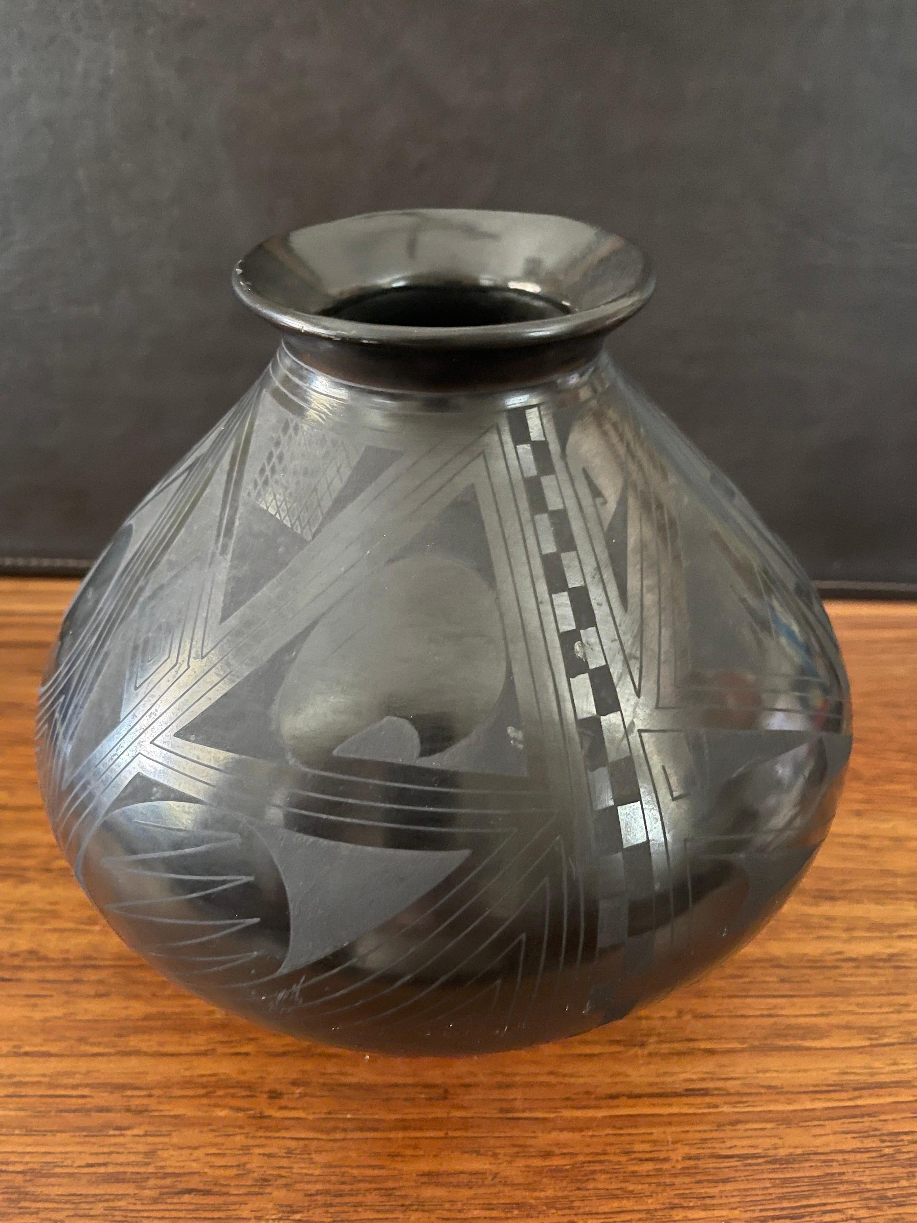 Beautiful hand-turned geometric blackware vase by Octavio Andrew, circa 2000s. The exquisite piece made of naturally black clay has a unique geometric design. This vase is in very good condition and measures 9.5