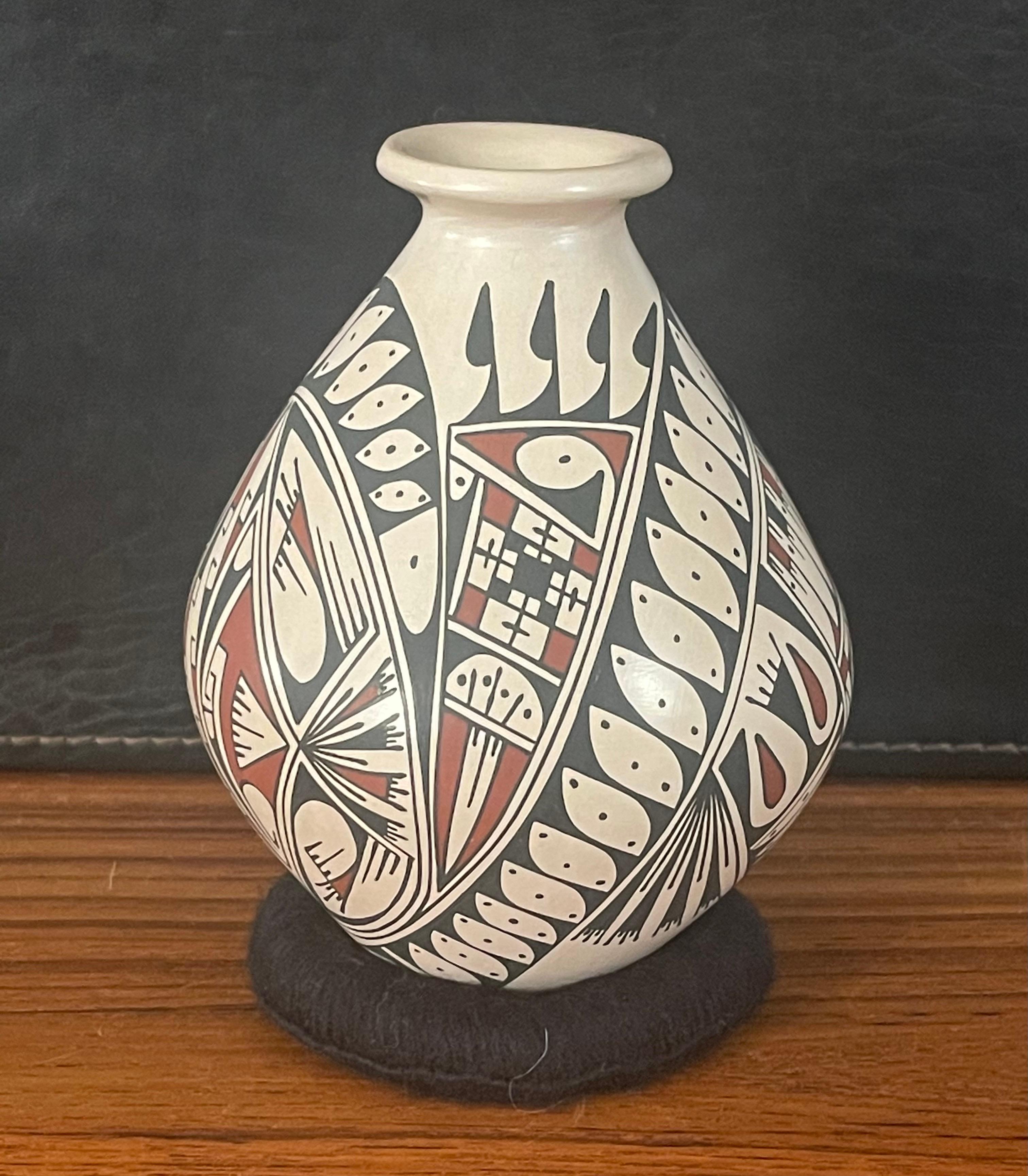 Beautiful hand-turned Mata Ortiz polychrome pottery vase with geometric motif by Oscar Quezada, circa 1990s. The exquisite piece made of naturally brown clay has a unique black and brown fish design. This vase is in very good condition and measures