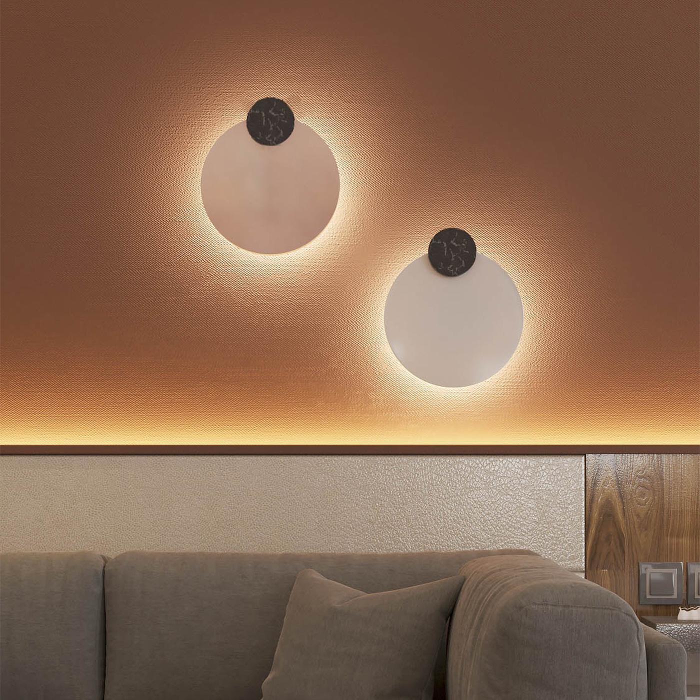 La bailarina exótica y espía holandesa Mata Hari inspiró esta colección de cautivadoras lámparas de pared. Vertido en un plato opalescente, el vidrio fundido blanco adquiere una forma de disco que, decorado con un círculo de mármol oscuro en la