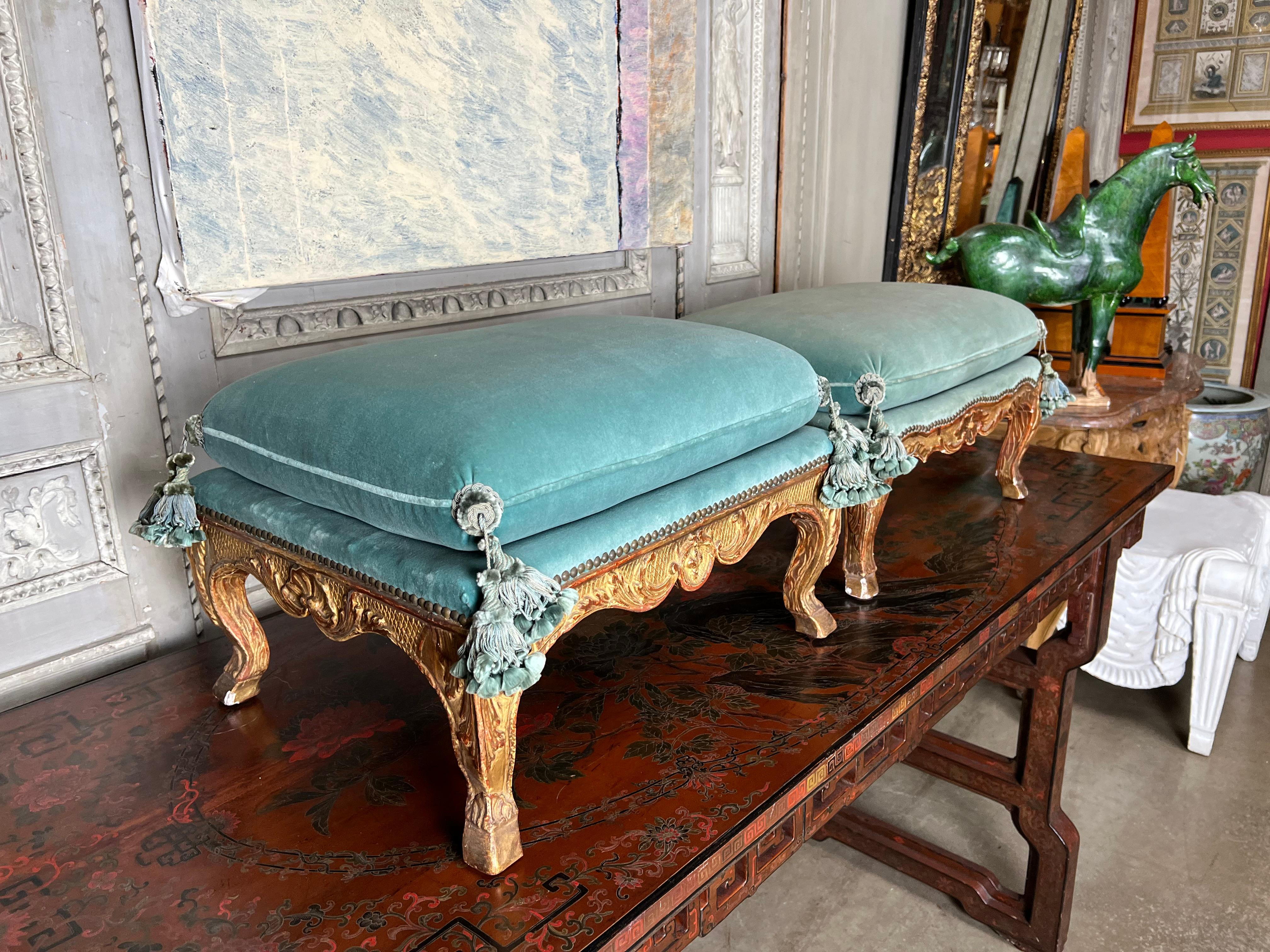 A matched pair of French gilt wood footstools in the Louis XV style dating form the late 19th century. These incredible footstools were obviously made by the same crafts person as they are both carved in their entirety. They are carved and gilded