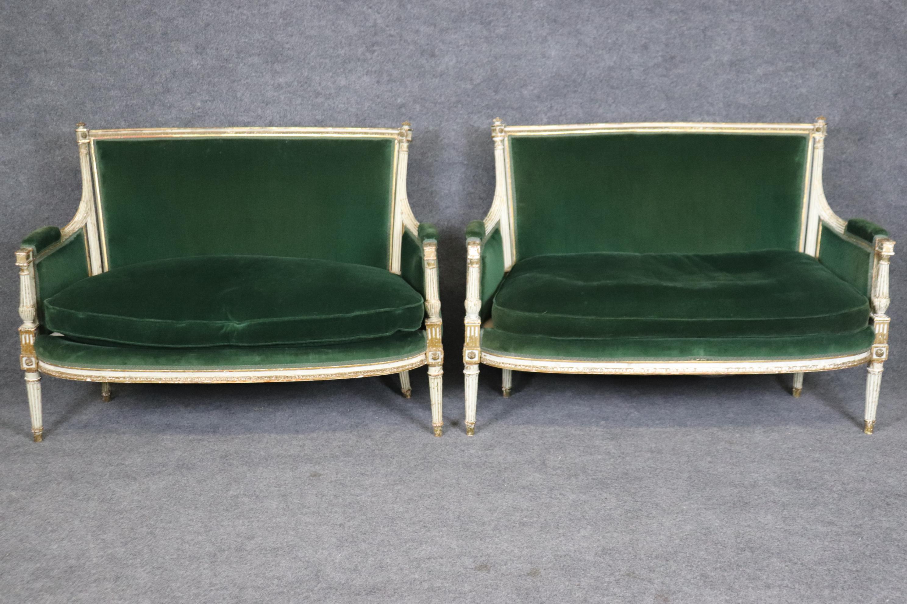 This is a very rare paid of lovingly distressed white and gold leaf decorated settees or canapes with gorgeous deep green velvet upholstery in good used condition. The frames are authentically distressed from being cleaned and polished over 120