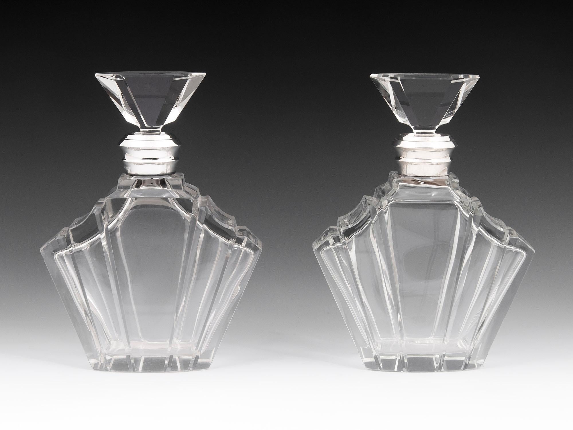 Pair of Art Deco uniquely fan-shaped heavy lead crystal decanters with beautiful step shoulder design, sterling silver collars and beautifully shaped stoppers.
This exquisite decadent pair of luxurious decanters bare the hallmarks for two famous