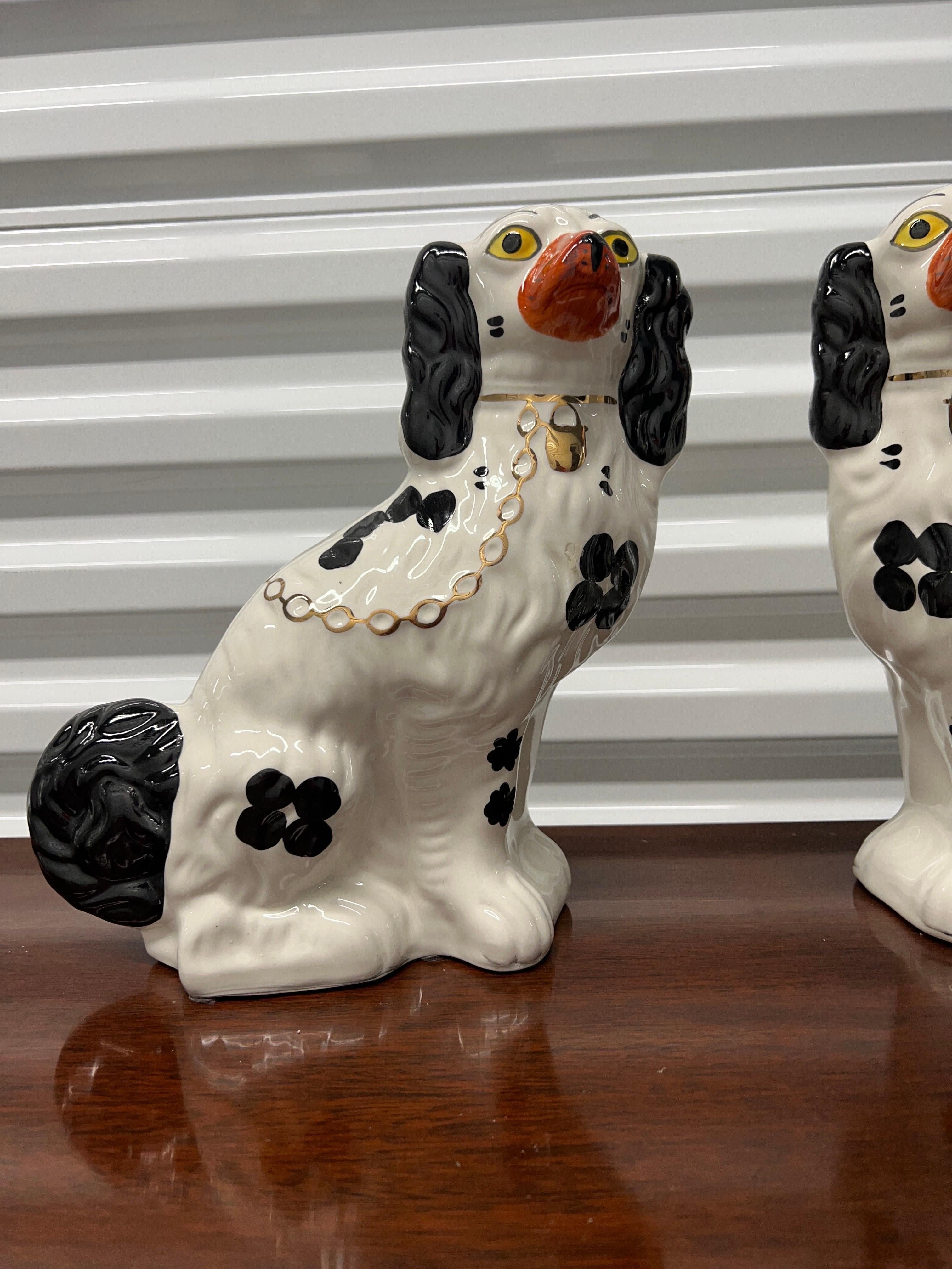 Matched Pair of Arthur Wood Staffordshire Spaniel Dogs each having a white body with black tail, spots, ears and traditional key lock chain to body. 

Each spaniel marked to underside appropriately.
