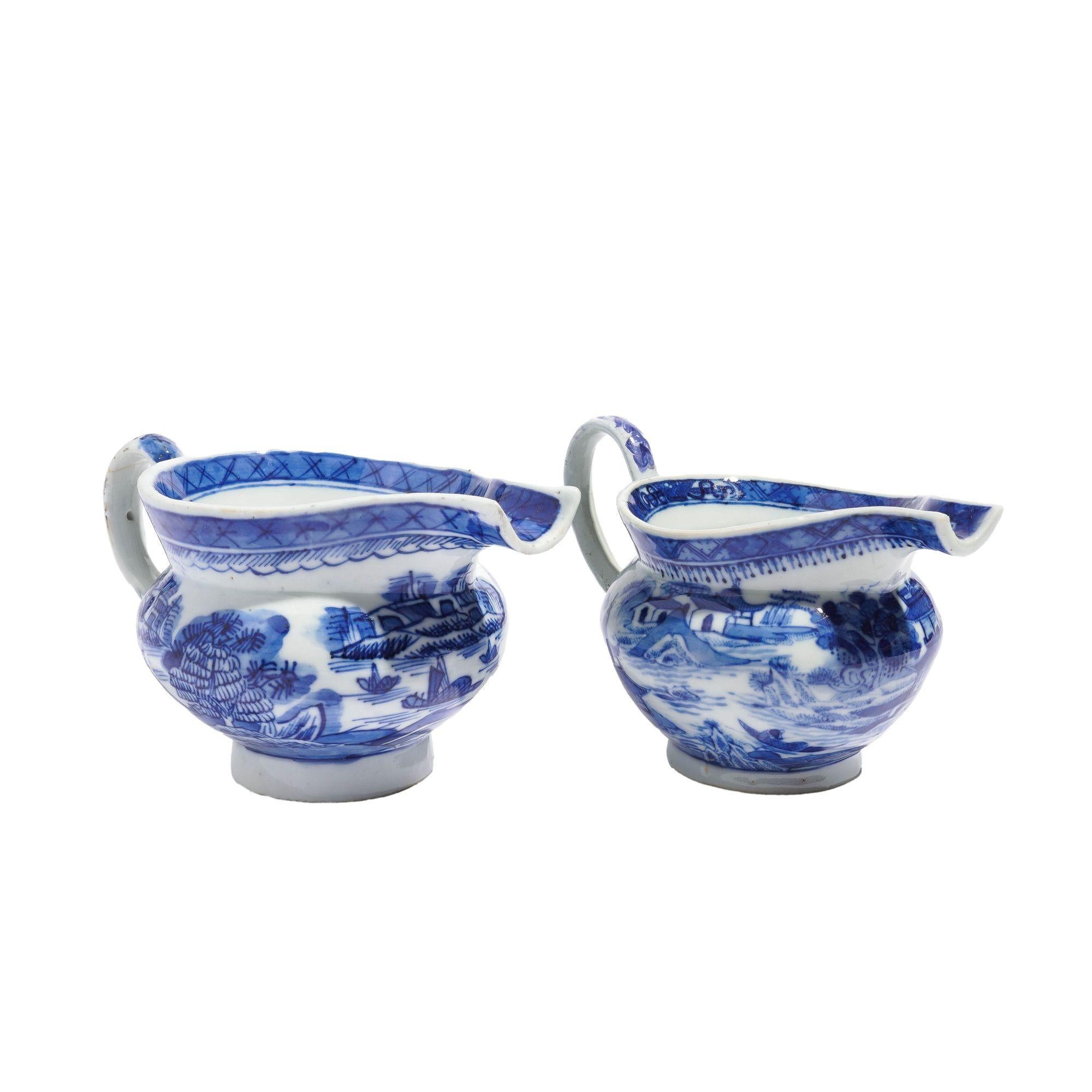 Matched pair of Chinese export porcelain pig snout creamers with applied loop handles. The body of the creamers are decorated with the Willow Tea House scene in cobalt underglaze blue. One creamer has the Canton cloud border the second creamer has