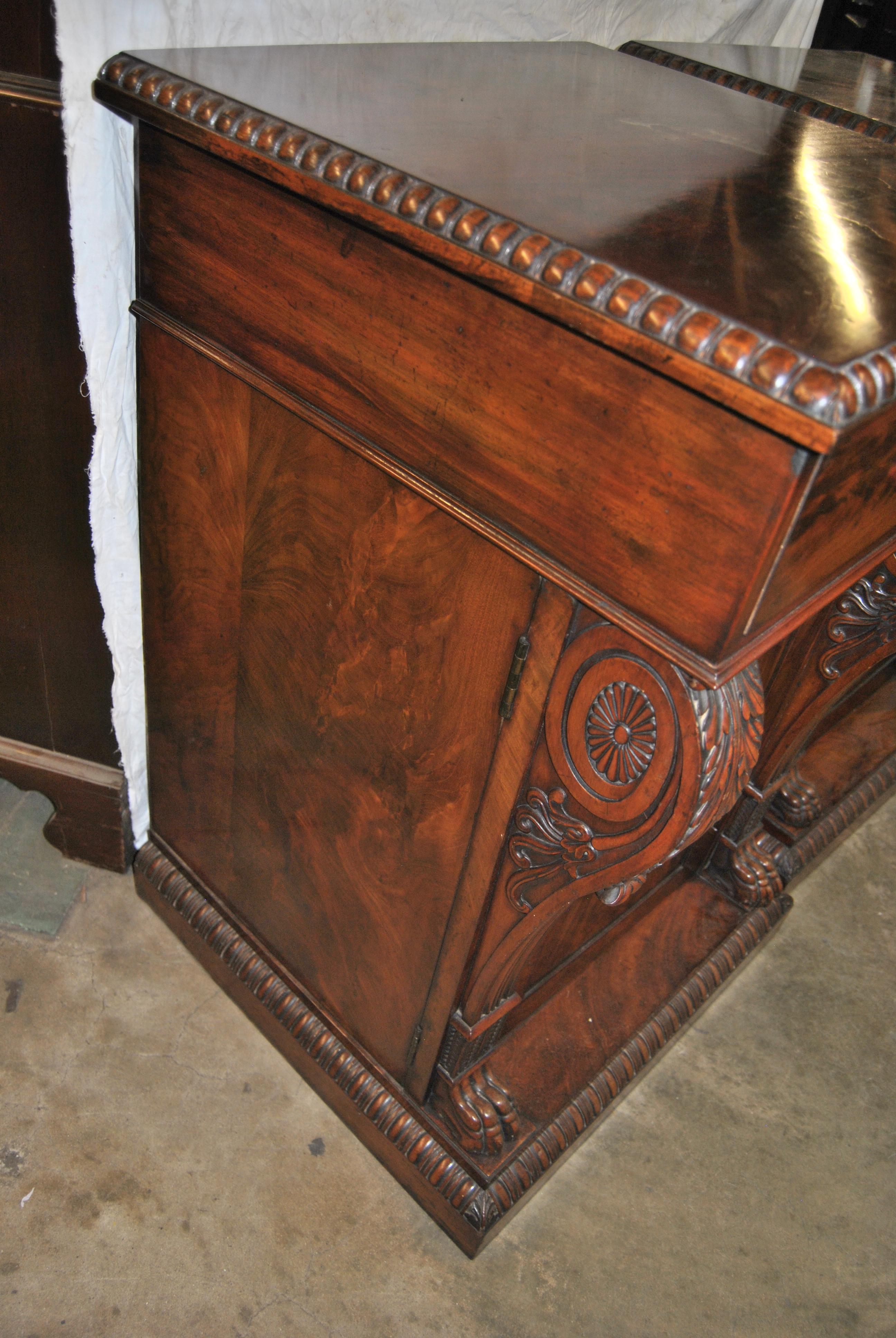 This is a matched pair of carved mahogany pedestals / stands / cabinets / cupboards made in England, circa 1860. There is a beautifully hand carved molding to the top and base of each pedestal. Each pedestal has a drawer over a cabinet door. This is