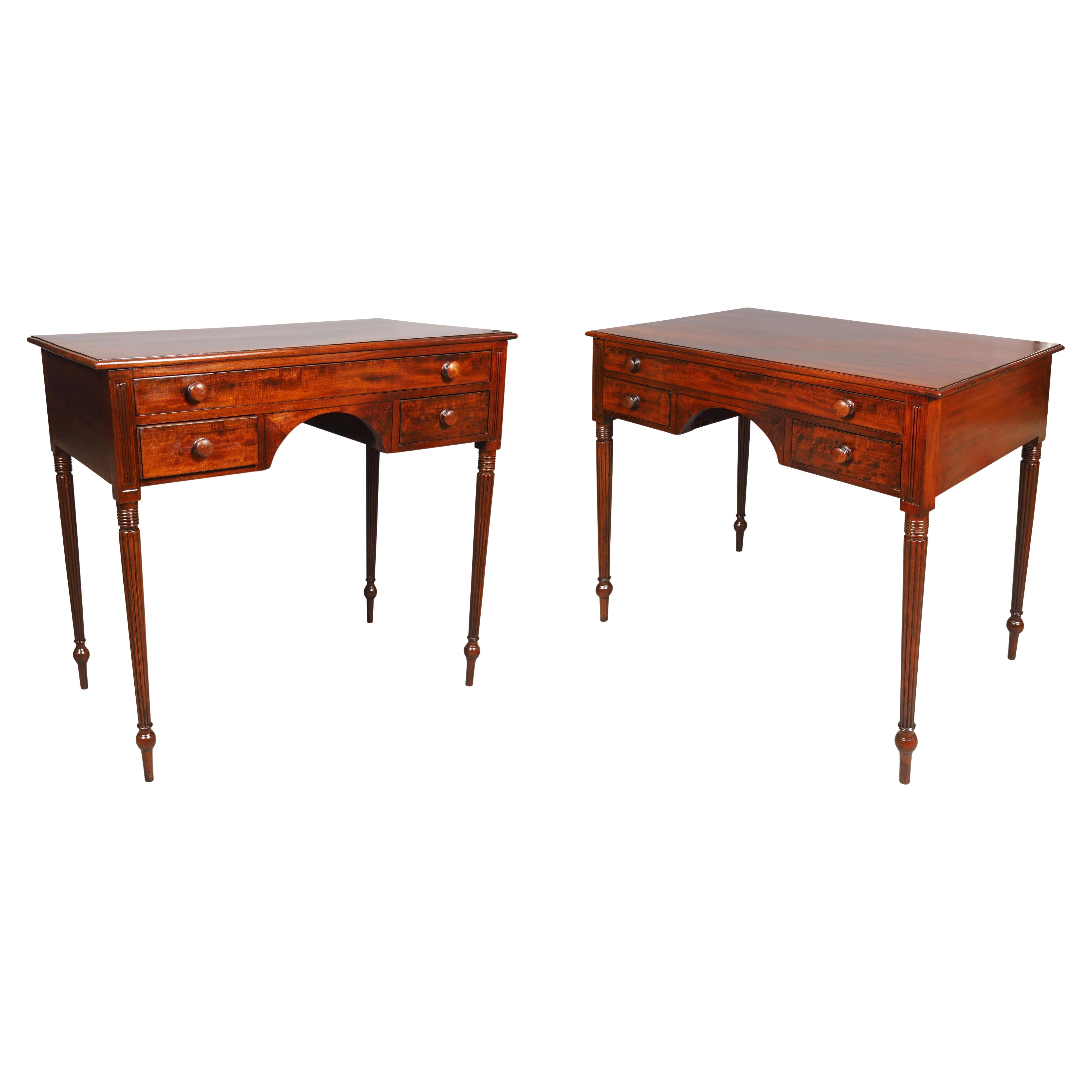 Each with a rectangular top over a long drawer and a pair of small drawers all with wood knobs surrounding an arched apron. All flanked by reeded carving and each with circular tapered reeded legs.
