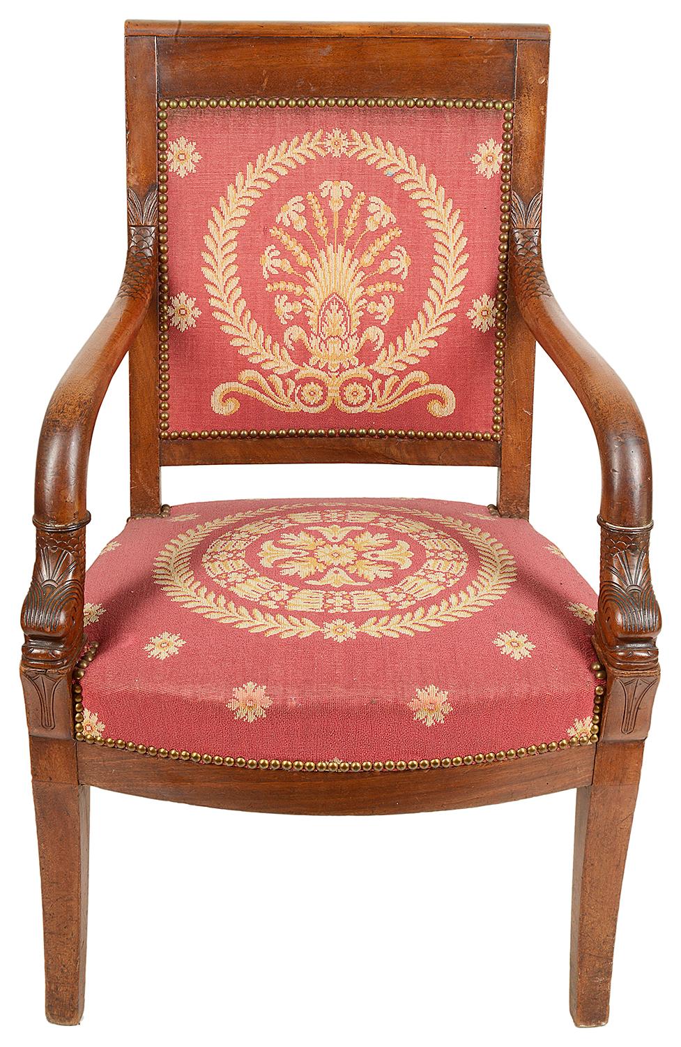 A good quality near pair of French Mahogany Empire influenced armchairs. Each being upholstered in a classical damask patterned burgundy fabric, polished back rail, Dolphins carved to the base of each arm, raised on elegant out swept legs.
