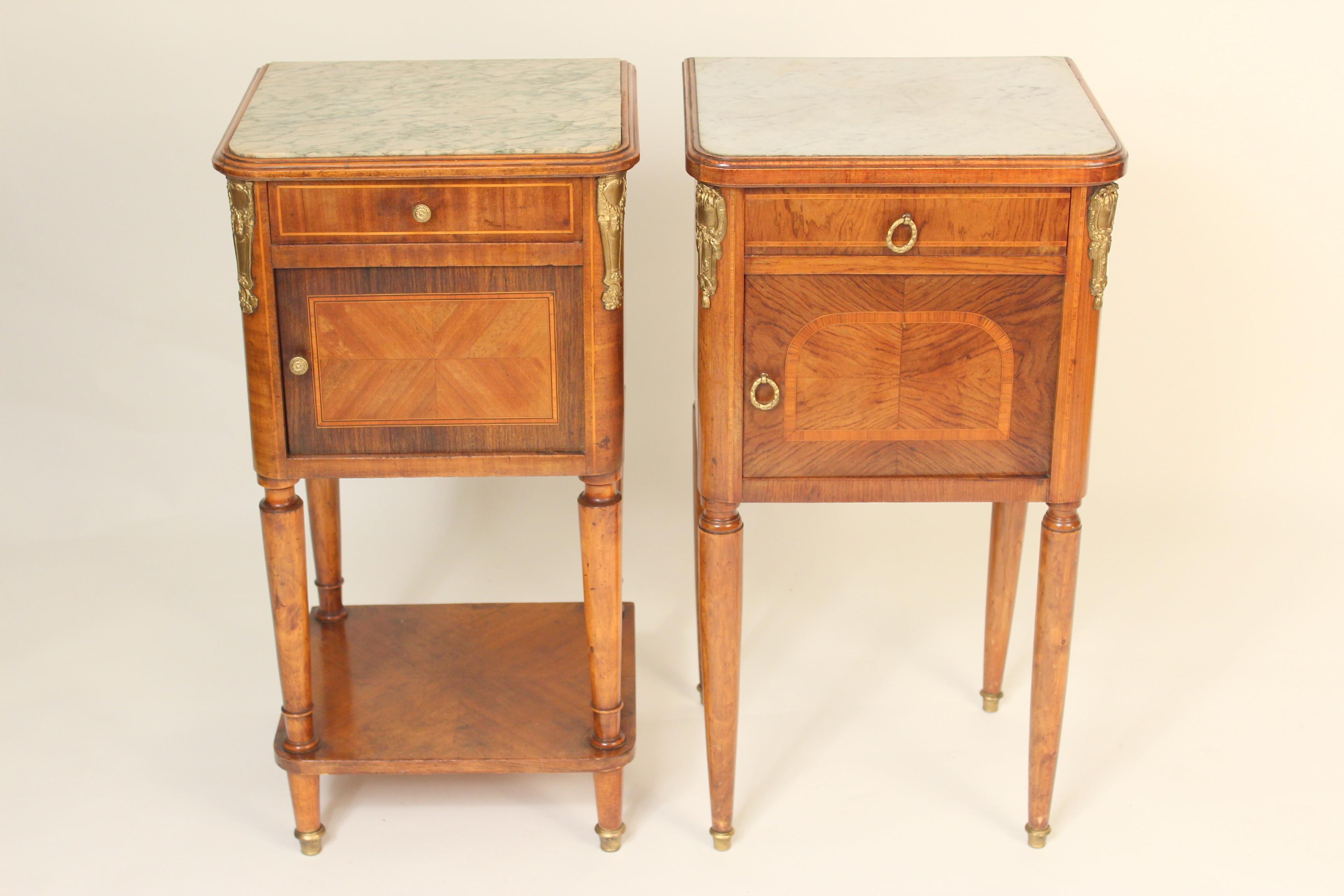 Matched pair of Louis XVI style gilt bronze mounted occasional tables with marble tops, circa 1930s. Both tables are lined with marble inside the doors. There are variations between the two tables. One is primarily tulip wood the other is primarily