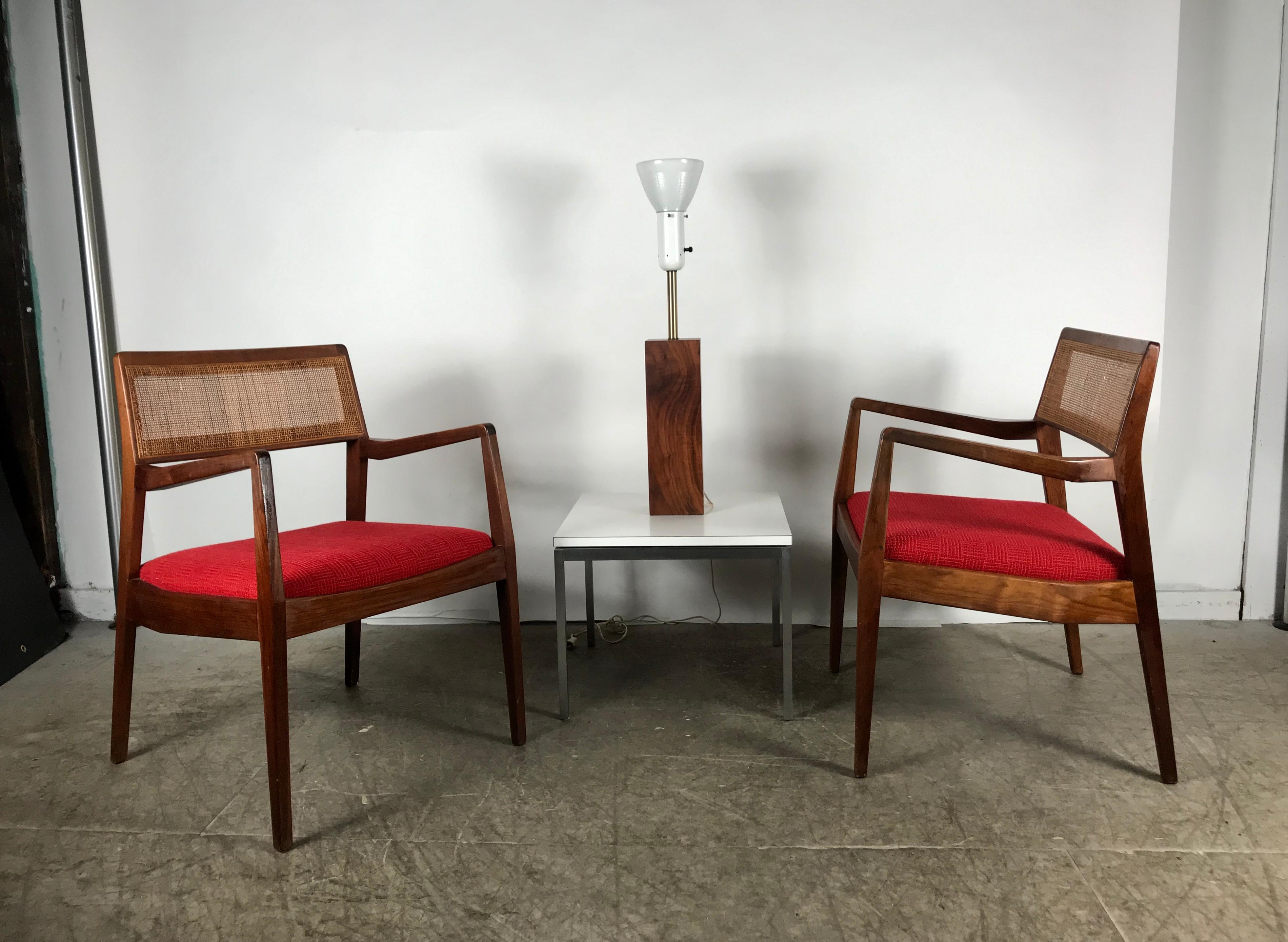Matched pair of modernist Jens Risom walnut and caned back lounge chair, beautiful original condition, extremely comfortable, retains original red wool fabric seat, also retains original Jens Risom Design inc. Silk label.