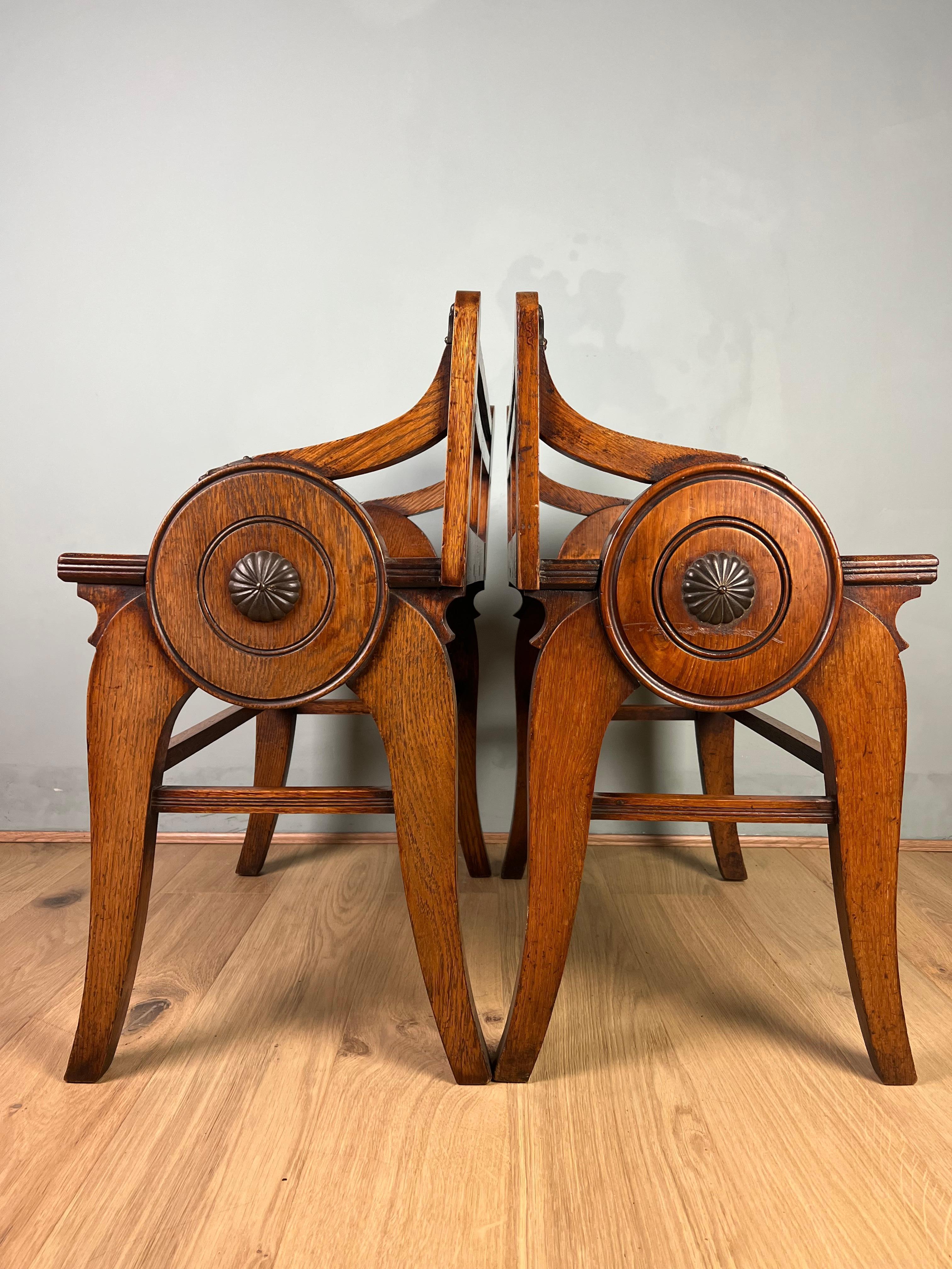 A matched pair of oak Schoolbred benches/stools in the Aesthetic style, one with the kite mark stamp to the back rail. Both benches are a pleasant light honey colour retaining its original patina. The benches have there original brass baluster back
