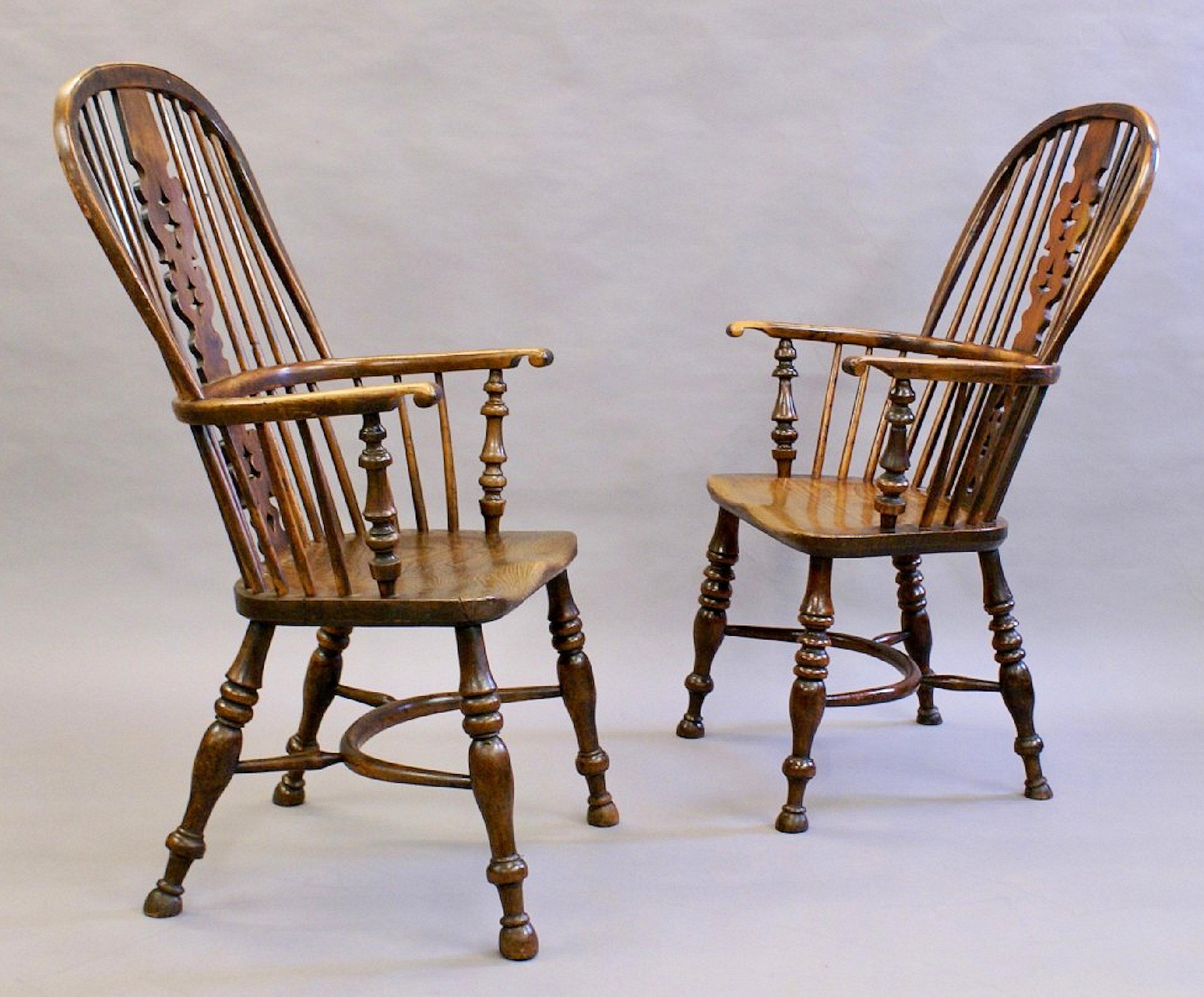 These beautifully simple yet gracefully shaped matched pair of Yew wood arm chairs feature hooped backs and arm rails with central pierced ornate back splats. The saddled seats are supported on 4 turned legs joined by a curved central stretcher bar.