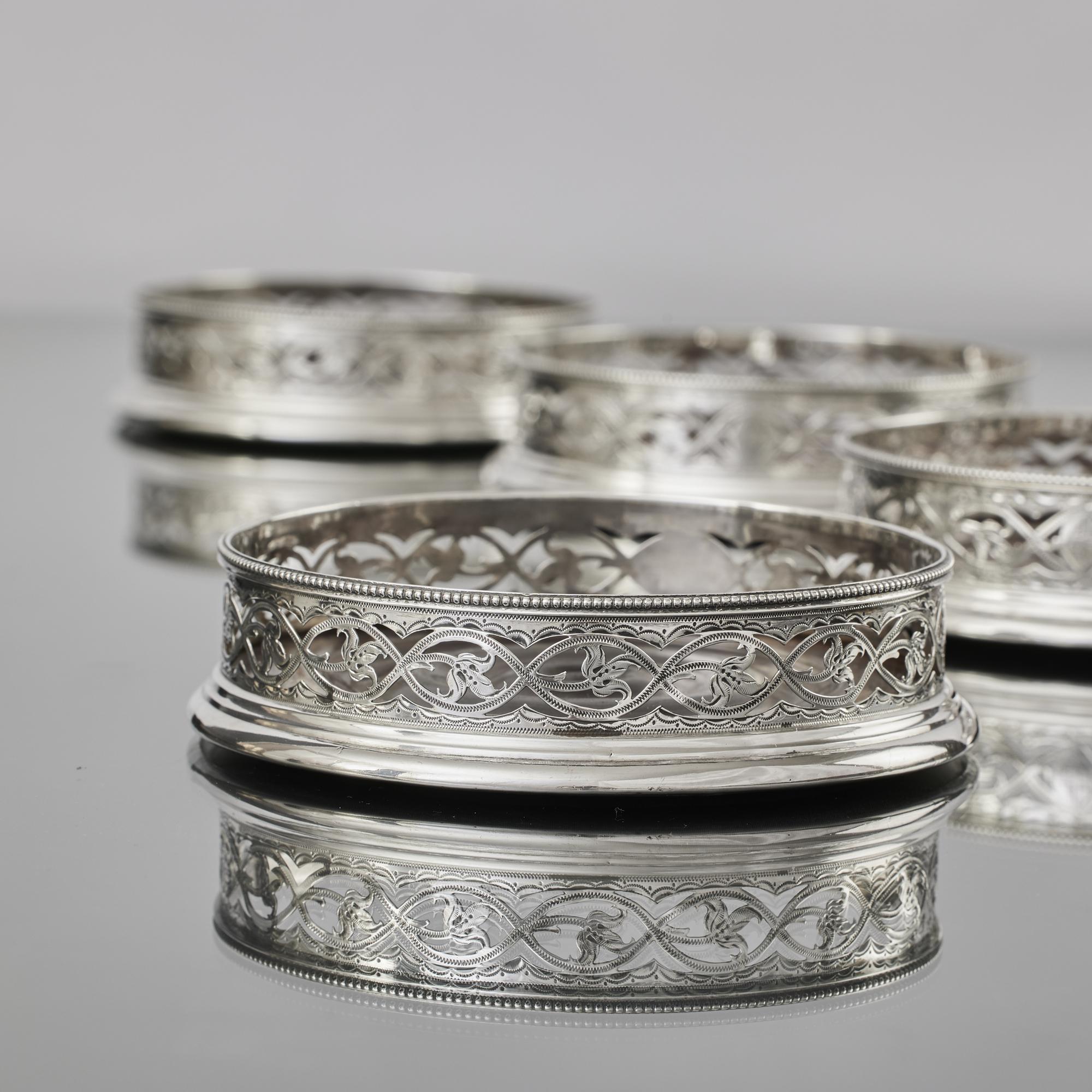 A particularly pretty matched set of four Georgian silver coasters was made by William Plummer in the late 18th century. The body of each wine coaster features beautifully pierced and engraved leaf and scroll decorations. The top edges are decorated