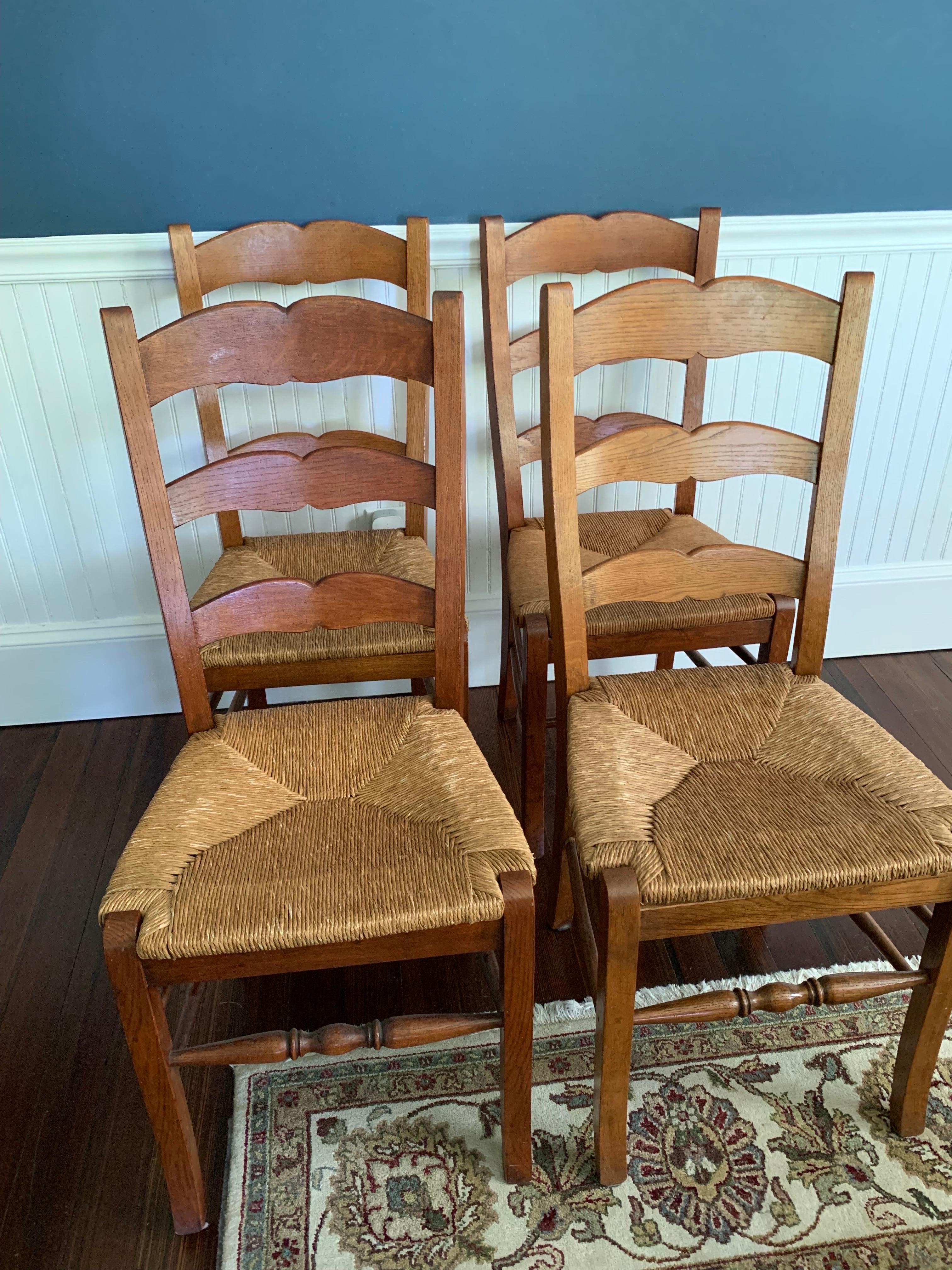 Matched set of four oak ladder back rush dining chairs
Rush seating very slightly different on each pair. Good overall condition, light wear.


Measures: Rush chairs: 
H - 38”
H of seat - 18”
D of seat - 16” 
W of seat - 17” at widest part;