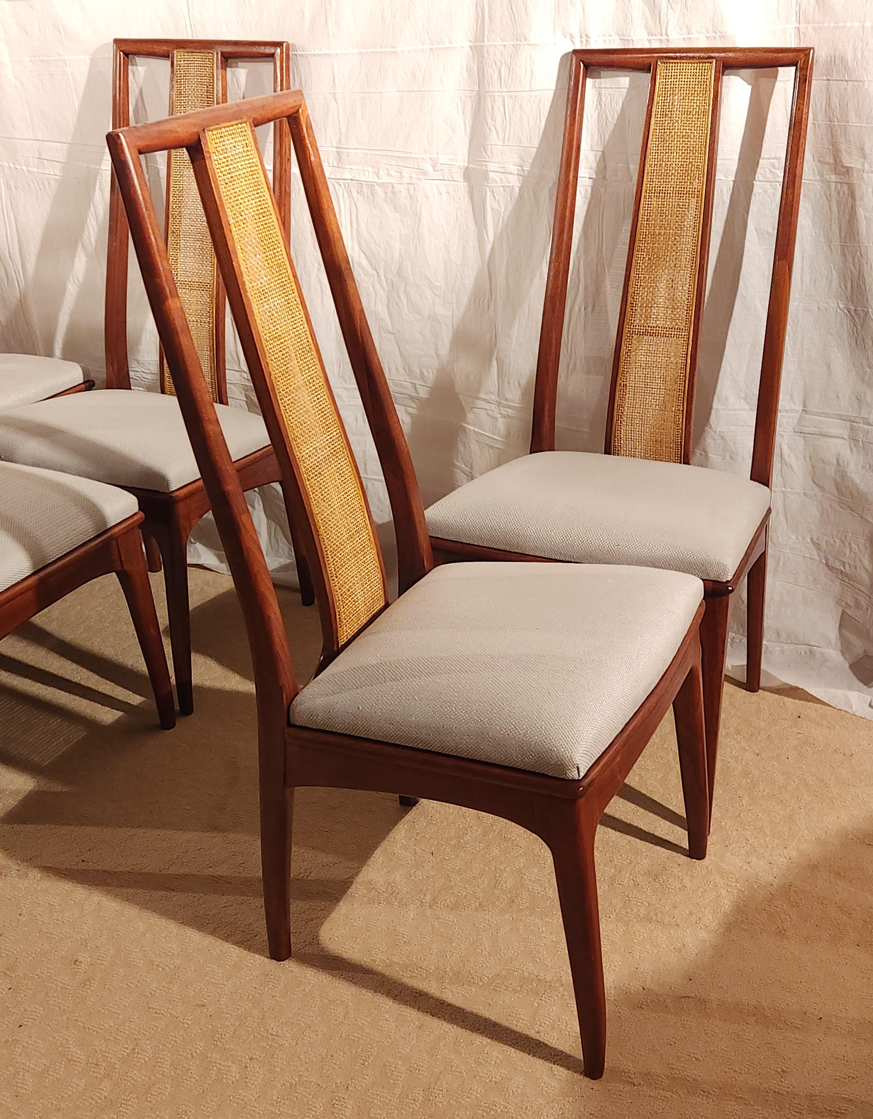 A matched set of six ( 6 ) dining chairs by John Stuart, circa 1960. Warm walnut frame with a caned inset on the back. 
The set consists of six ( 6) side chairs. 
The set is n excellent restored condition. New seat cushions upholstered in a fine