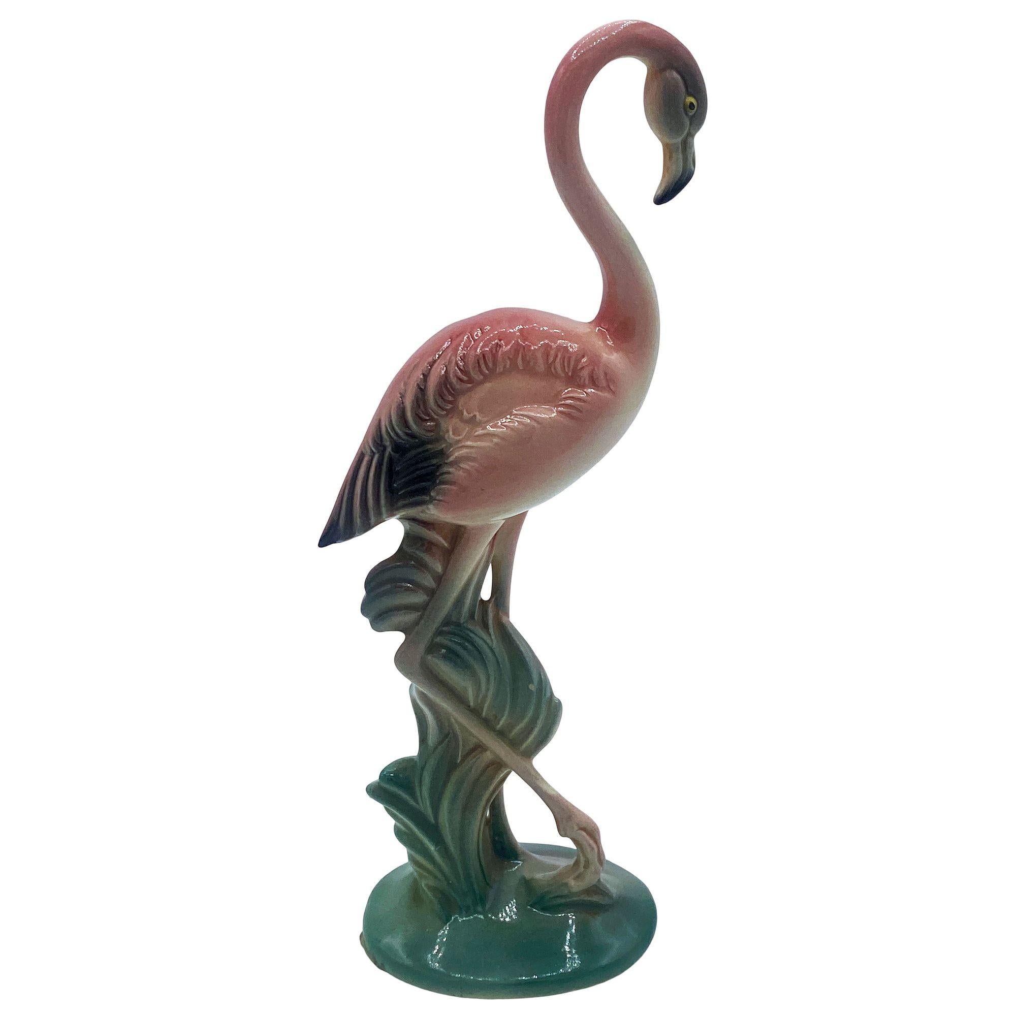 Mid-century pink and green matching California ceramic flamingo tabletop statues with the short statue by Brad Keeler. The set features two beautifully detailed pink flamingos in lush green leaves and grass with a pink color. Each comes with a gloss