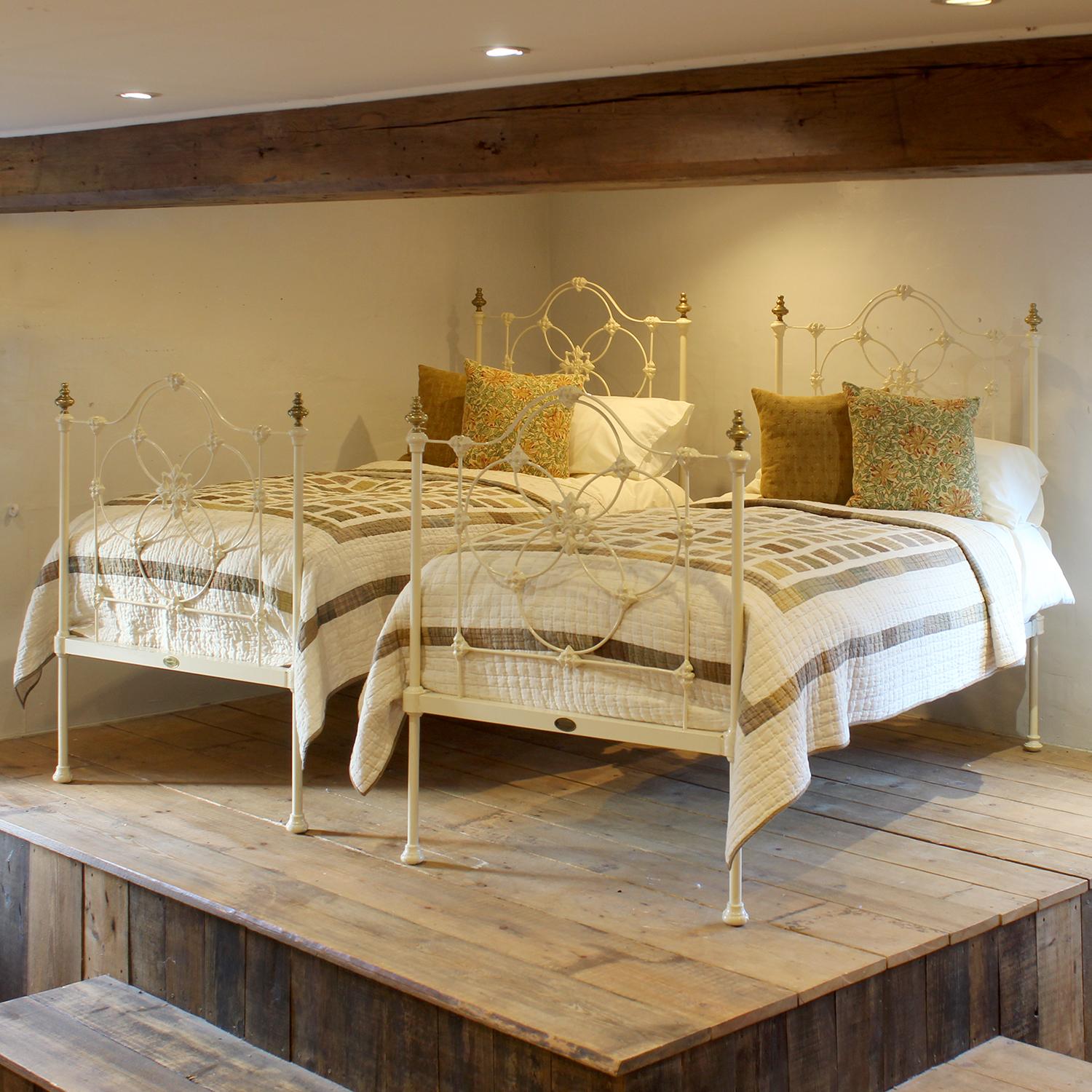 A matching pair of antique iron single beds from the mid-Victorian era, circa 1880, finished in cream with ornate castings and concentric circle design.

These beds accept standard UK single size 3'0