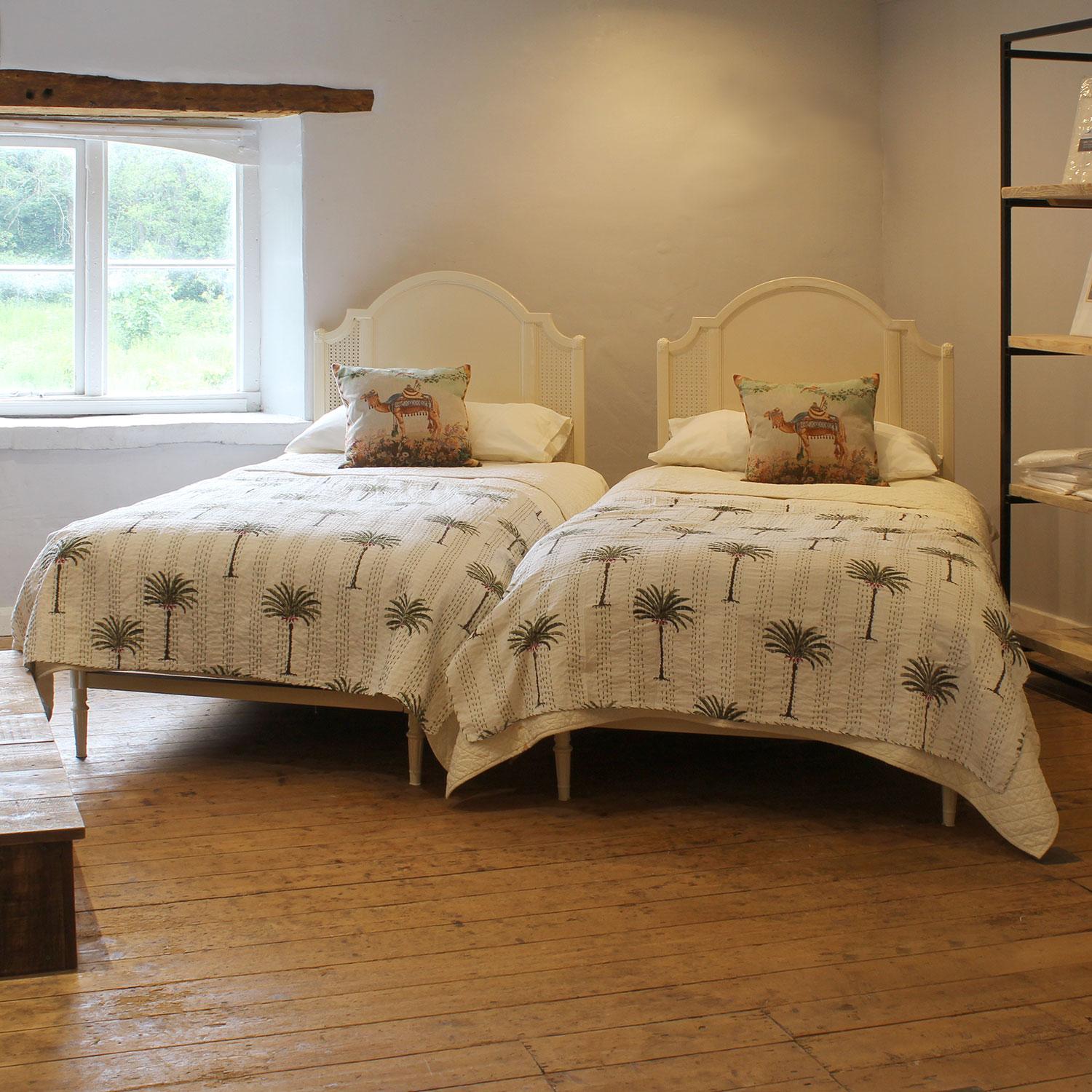 A matching pair of Art Deco style cast iron antique beds with arched backboards, fretwork side panels and decorative front legs, finished in cream.
These beds accept either US Twin size 3'3