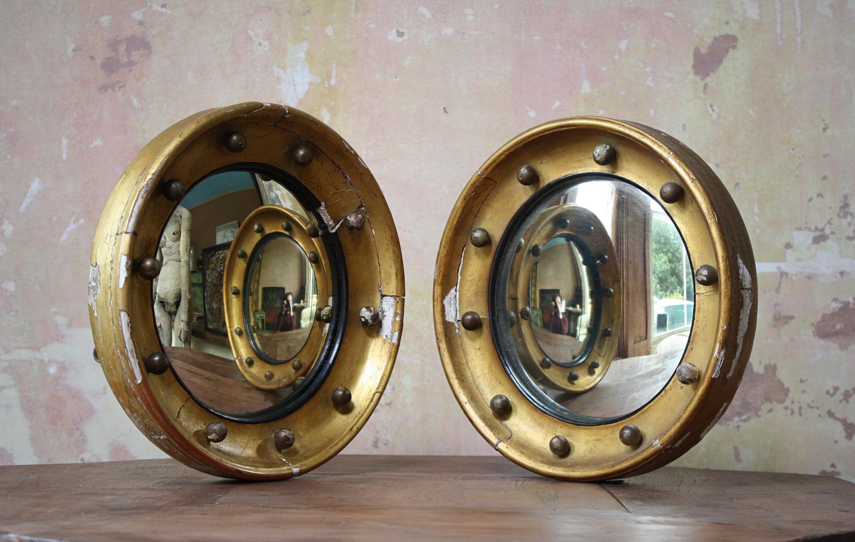 A matching pair of early 19th century convex mirrors, with typical ball decoration, faux ebonised slips and gilt work. 

The mirrors are in very much untouched condition with losses to the gilding and gesso, some very minor foxing to the mirror