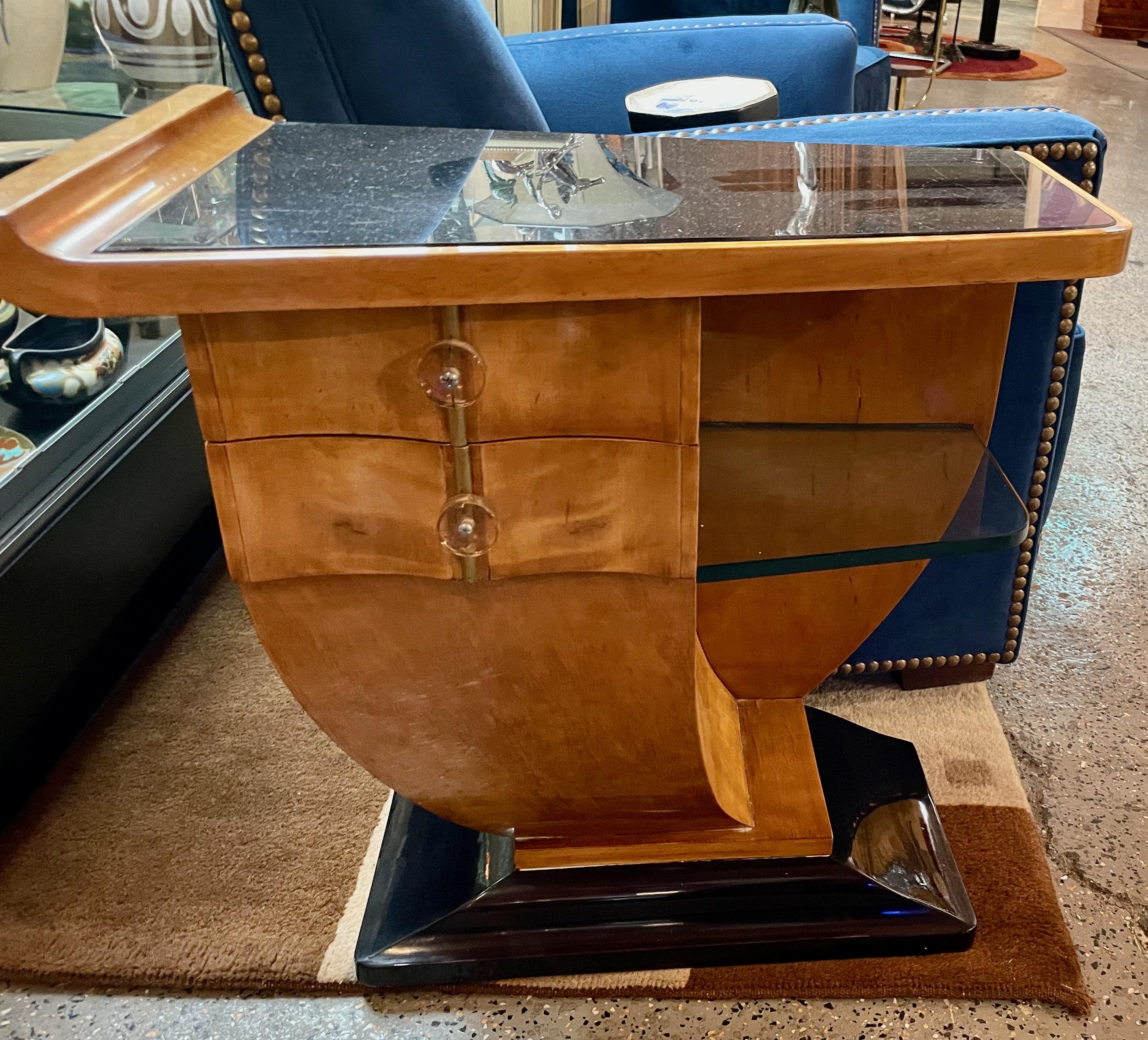 Matching pair of end tables Honey Blonde wood with Vitrolite glass tops. In an unusual asymmetrical shape, both tables have a pair of drawers with original lucite handles. Recently restored wood, beautiful wild grain, and original black vitrolite