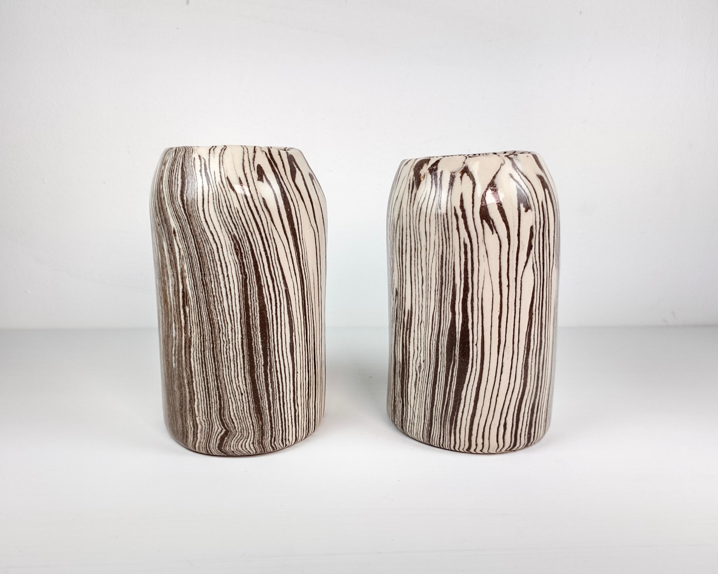 Each vase is formed by putting a slab of alternating clays together before forming into a cylinder and sculpting to the finished shape. Before each firing stage, the clay smudges are sanded and polished away to create sharpness and definition