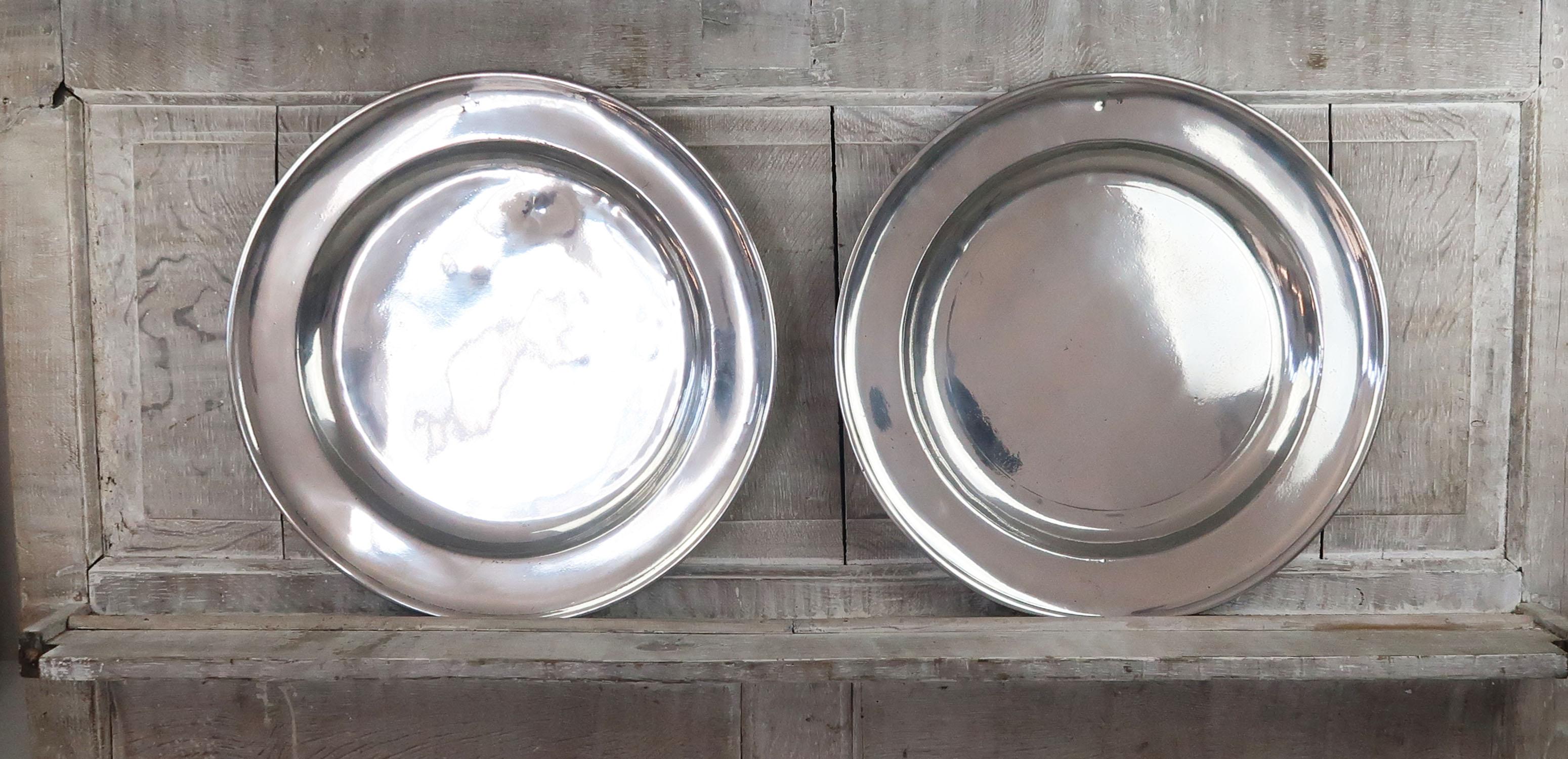 2 great highly polished pewter chargers. Measure: (18 inches).

English, late 18th century

The same ownership inscription on the front rim of both of them.

Rubbed touch marks on the underside. Probably a London maker.

The pewter has been