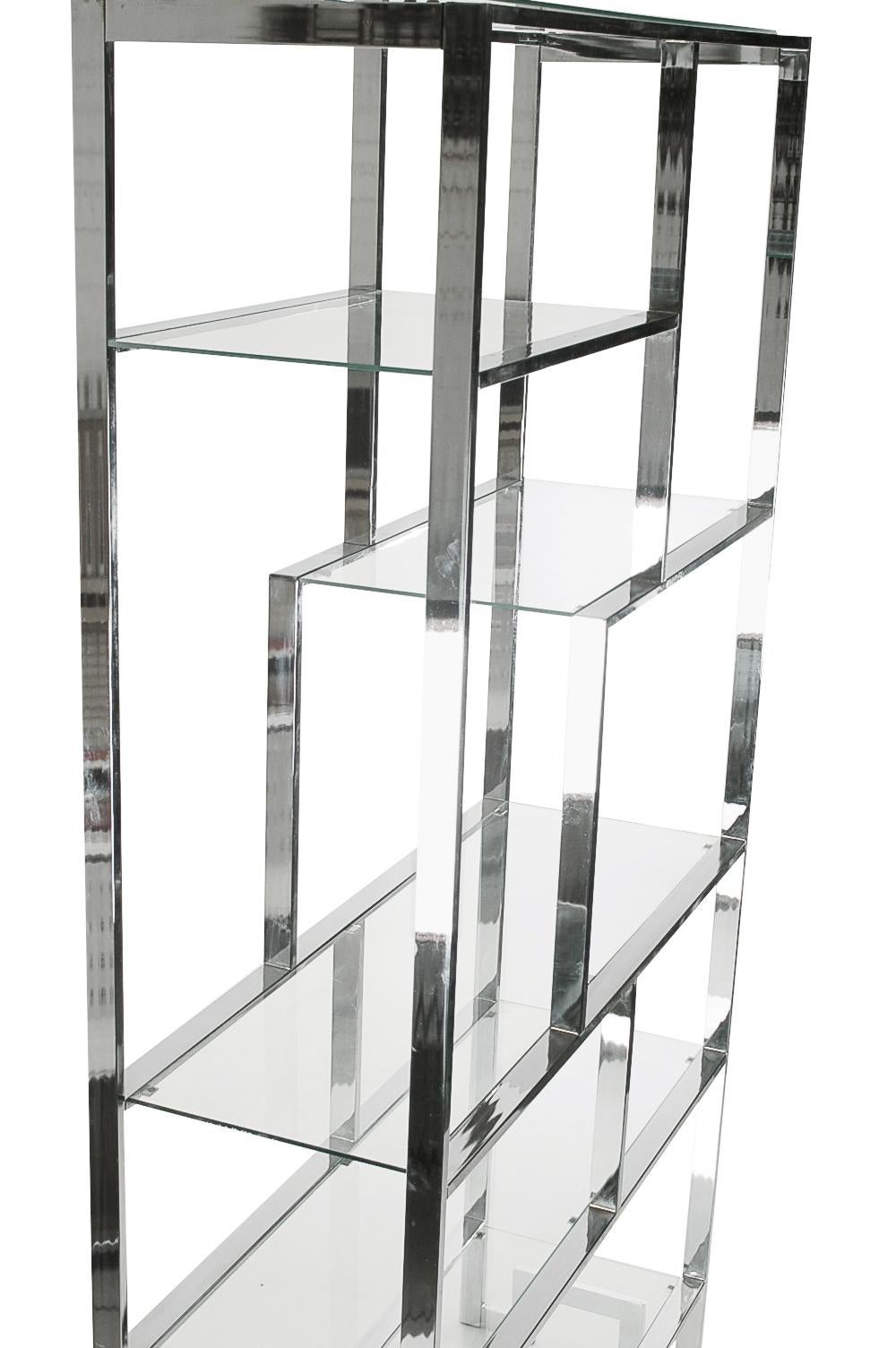 A pair of large asymmetrical chrome and glass etageres in the style of Milo Baughman. It features a heavy chrome flat bar frame with various sized clear glass shelves. Very clean and ready for immediate use.