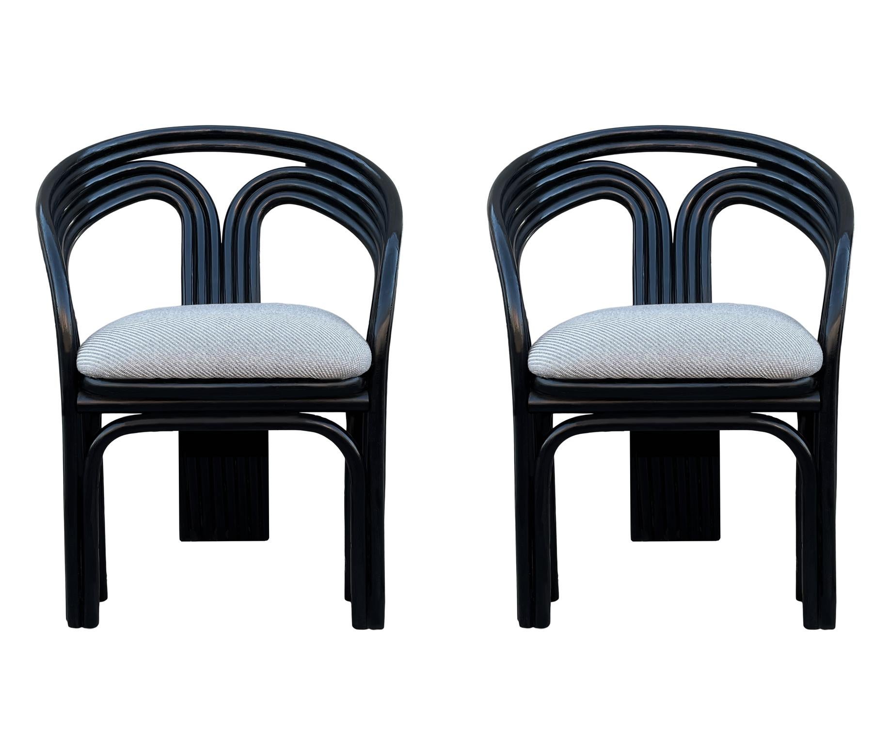 A sculptural pair of armchairs circa 1980's. These feature black rattan frames with light grey tweed cushions.