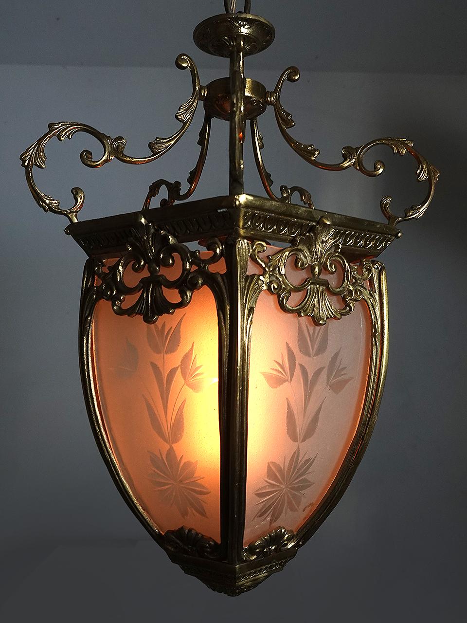 Si tratta di una coppia di lampadari/pendenti in stile lanterna dall'aspetto molto ricco. Le fusioni in metallo sono ornate e molto delicate. Ogni lampada ha 5 pannelli di vetro smerigliato tagliati a mano e trasparenti con un disegno floreale. Le