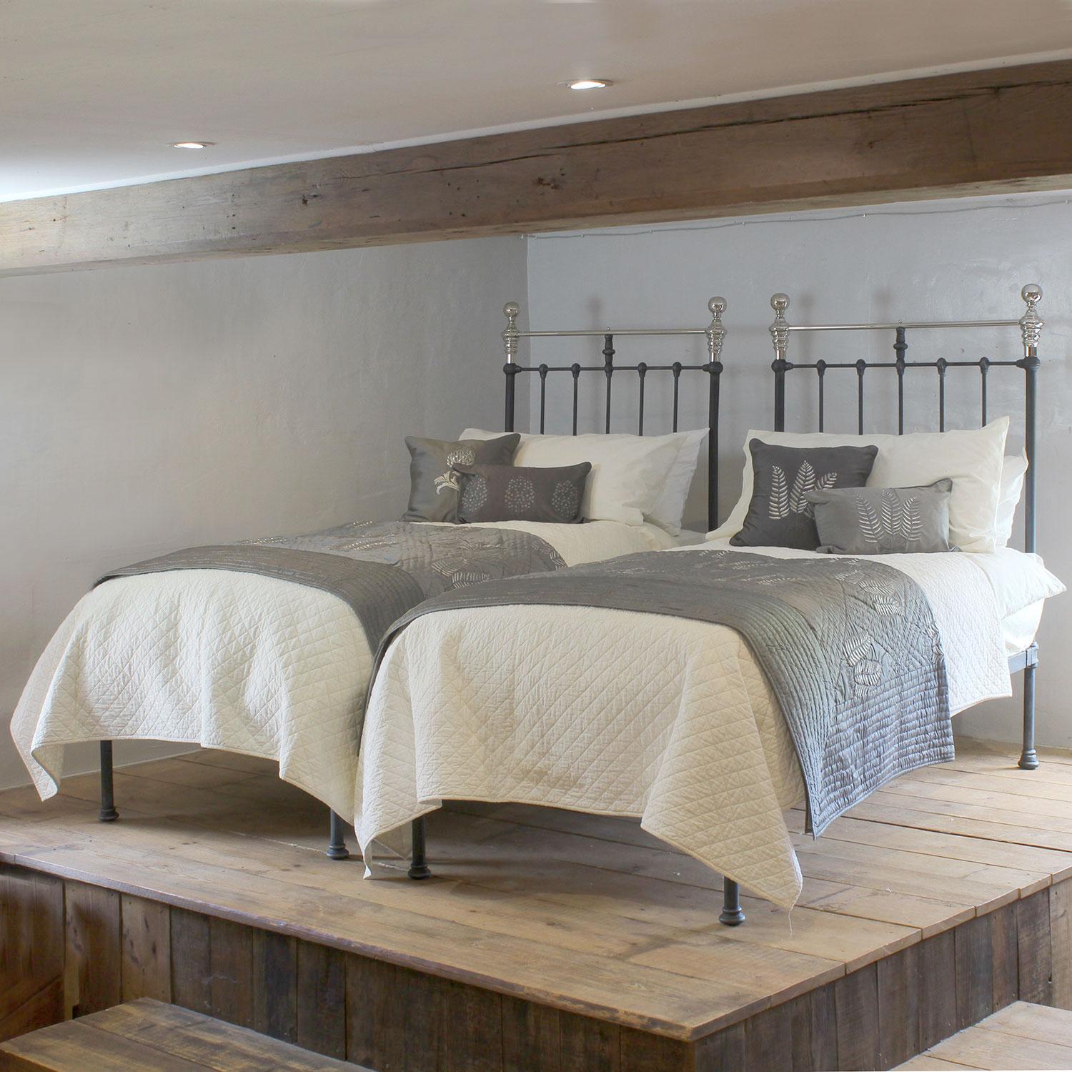 A matching pair of classic antique metal beds finished in Charcoal (black with silver) with nickel plated brass top rails, knobs and collars. This handsome pair are in an industrial style and would look stunning in both a traditional and a