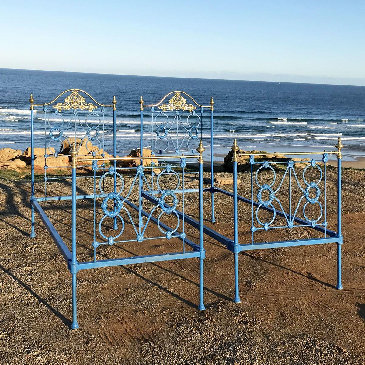 A matching pair of twin brass and iron antique beds with cast iron panels, ornate brass castings and serpentine brass top rails on the head ends.
These beds are currently in blue but can be repainted in a color of your choice.

These beds accept