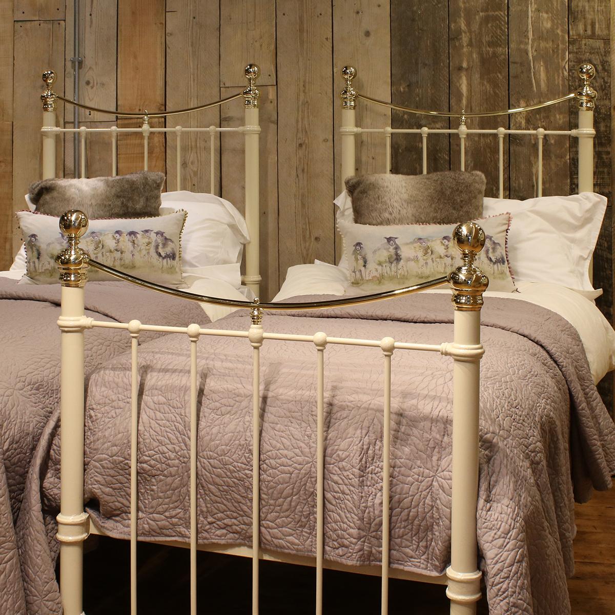 A matching pair of twin brass and iron beds finished in cream with curved brass top rails and 2