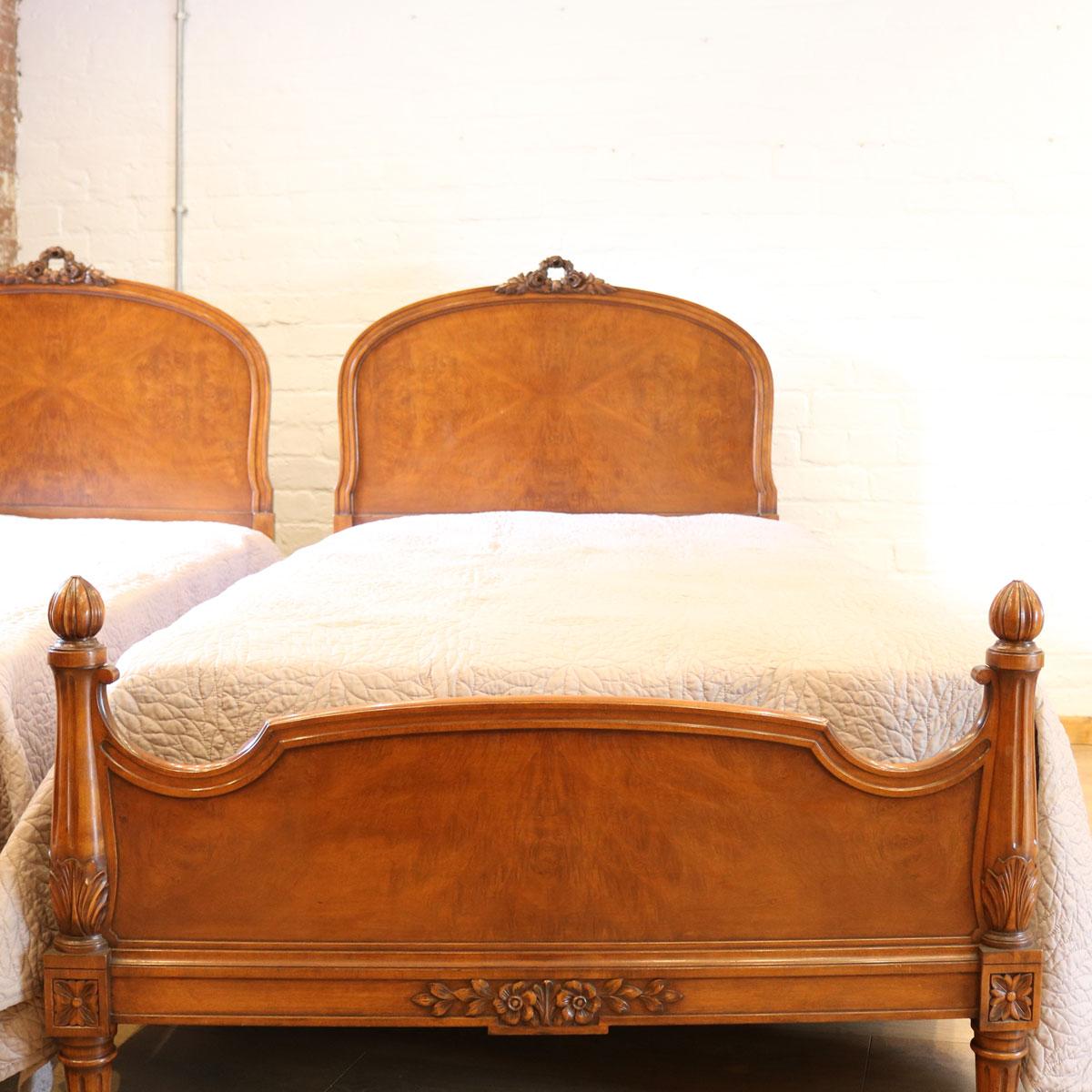 Matching pair of mid-20th century beds with elegantly arched head panels and rose garland carvings. The foot panels have attractive fluted and tapered posts.

The price is for the bed frame alone. The base, mattress, bedding and linen are extra