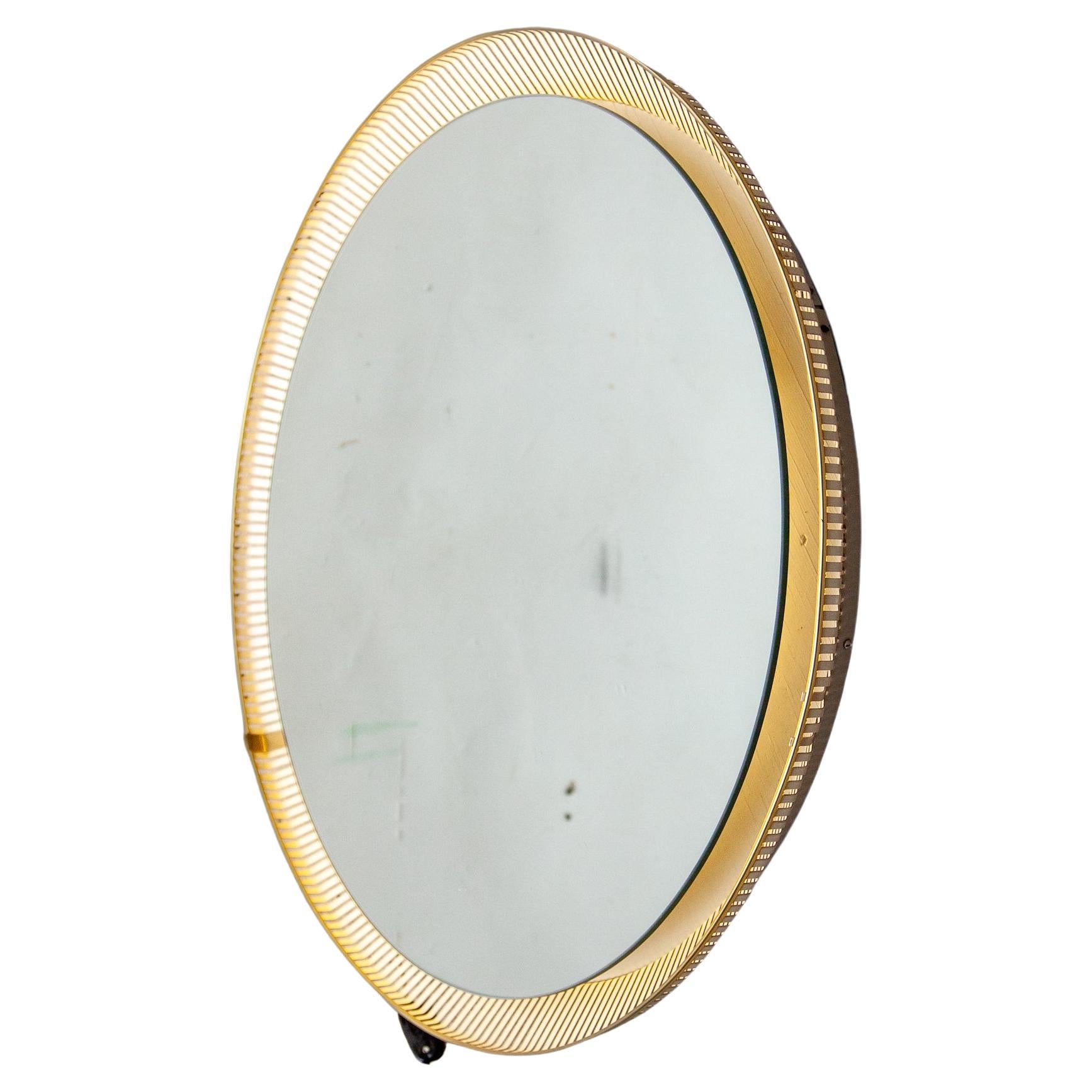 A beautiful round wall mirror perforated white metal base that holds three bulbs. The mirror with background lighting, designed in the Fifties by Mathieu Matégot and produced by Artimeta the Netherlands . The mirror works with a pull switch. An eye