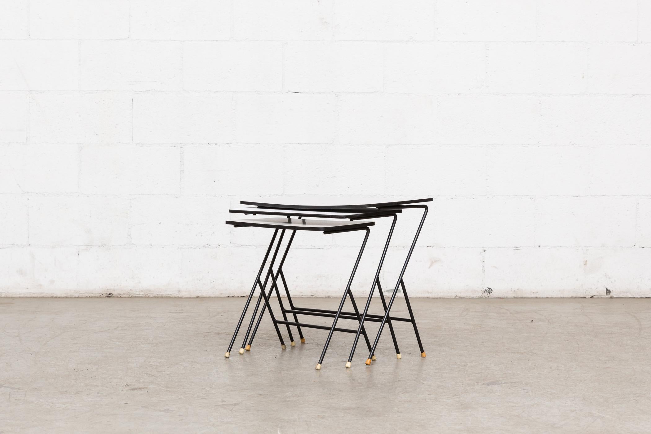 Set of 3 zig-zag mategot inspired nesting tables with grey and white Formica tops, black enameled metal wire frames and original rubber tipped feed. Visible cracking and staining to top table. Visible wear. Set price.
