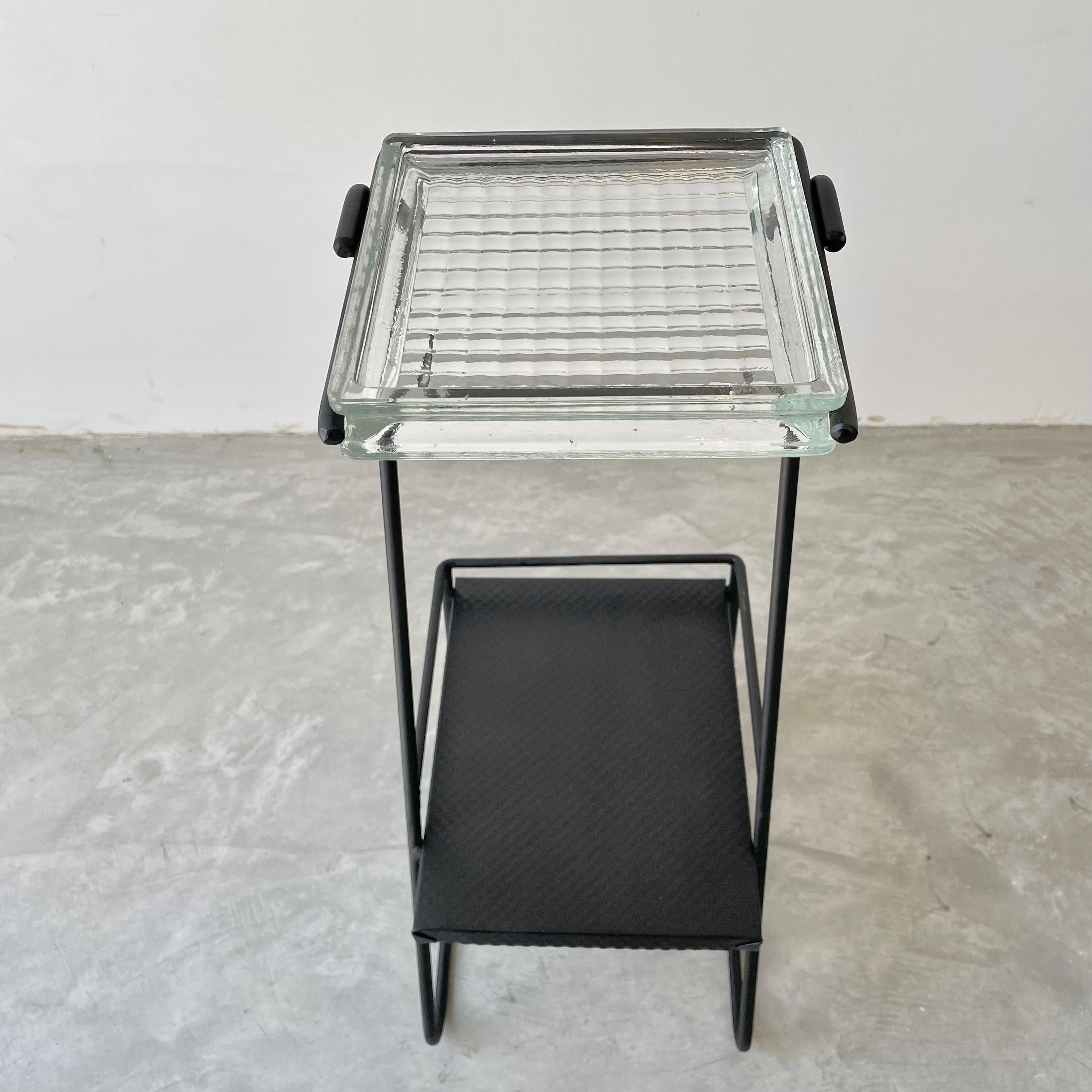 Beautiful two tiered side table/ashtray in a jet black iron frame. Upper level is a thick glass catchall held by two metal prongs. The bottom table is a textured black metal. Elegant and modern design perfectly contrasted with rustic materials and