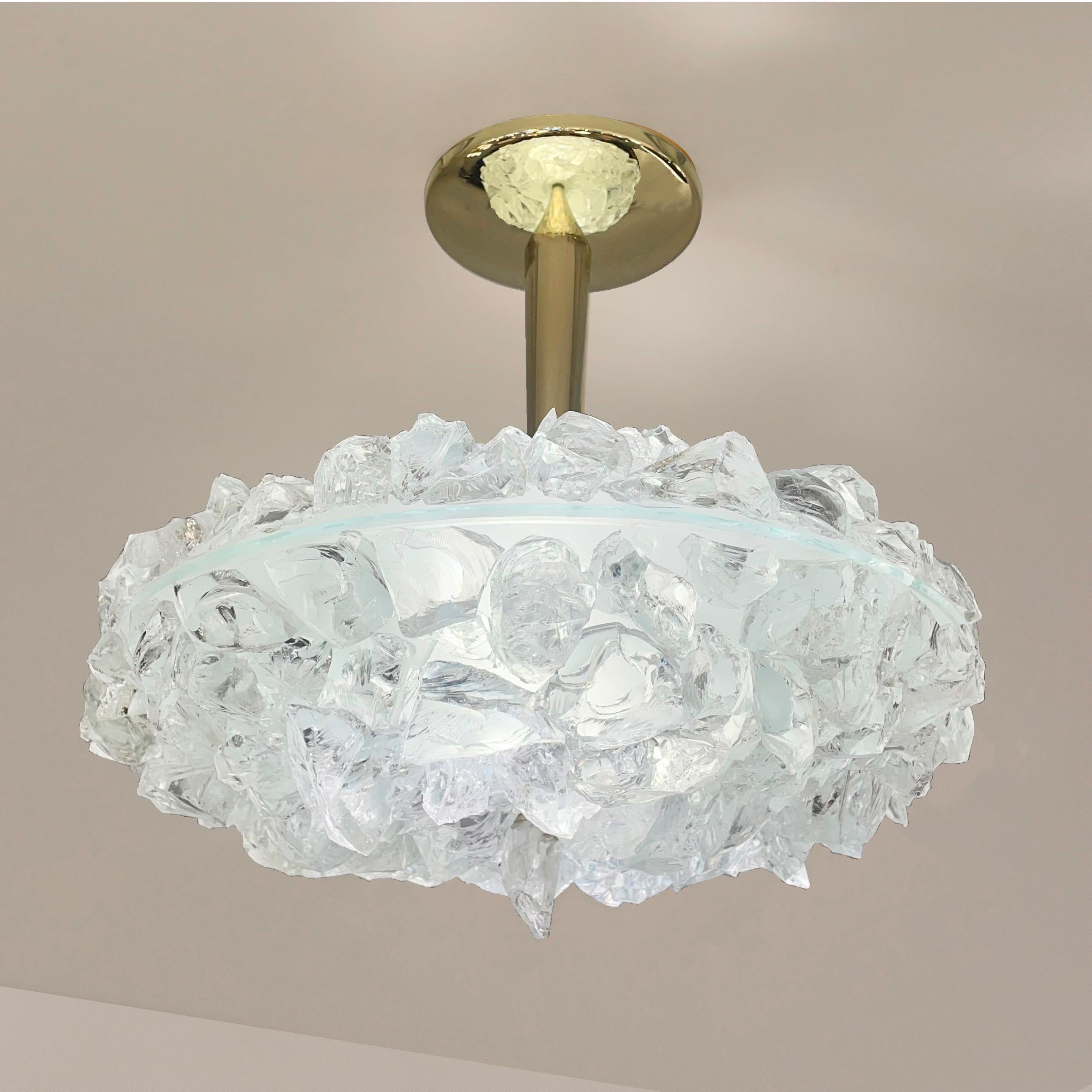 The focal point of the Matera ceiling light is the sculptural glass shade composed of dozens of hand applied crystal elements. Its clean and modern stem and canopy, create a balanced contrast to the organic feel of the rest of the piece. Shown with