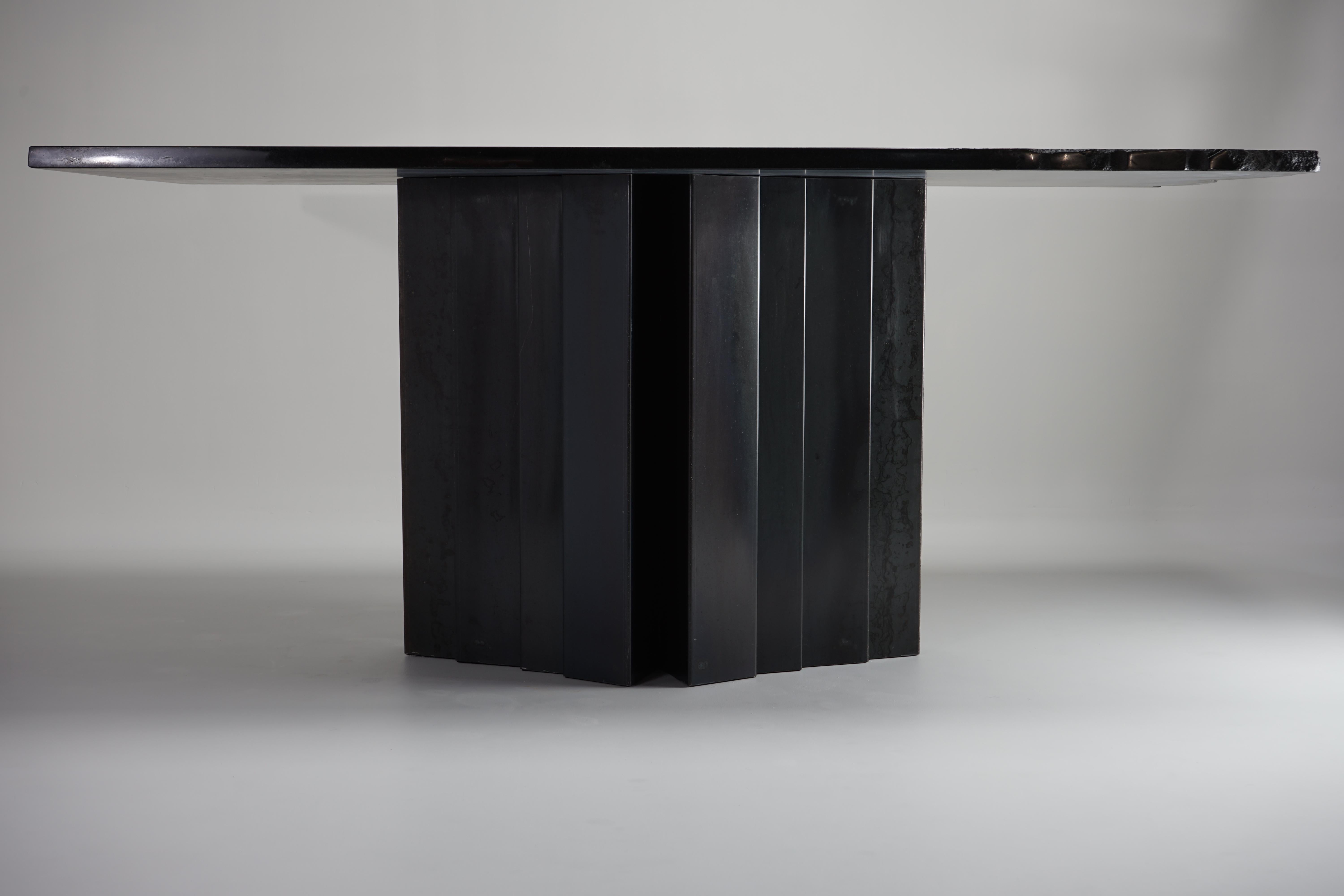The Materico Table is a uniquely architectural assemblage that combines the contrasting forms of a bold geometric base with the natural detail of its raw-edge top. 
Visually, this audacious table features a monolithic impact through the use of