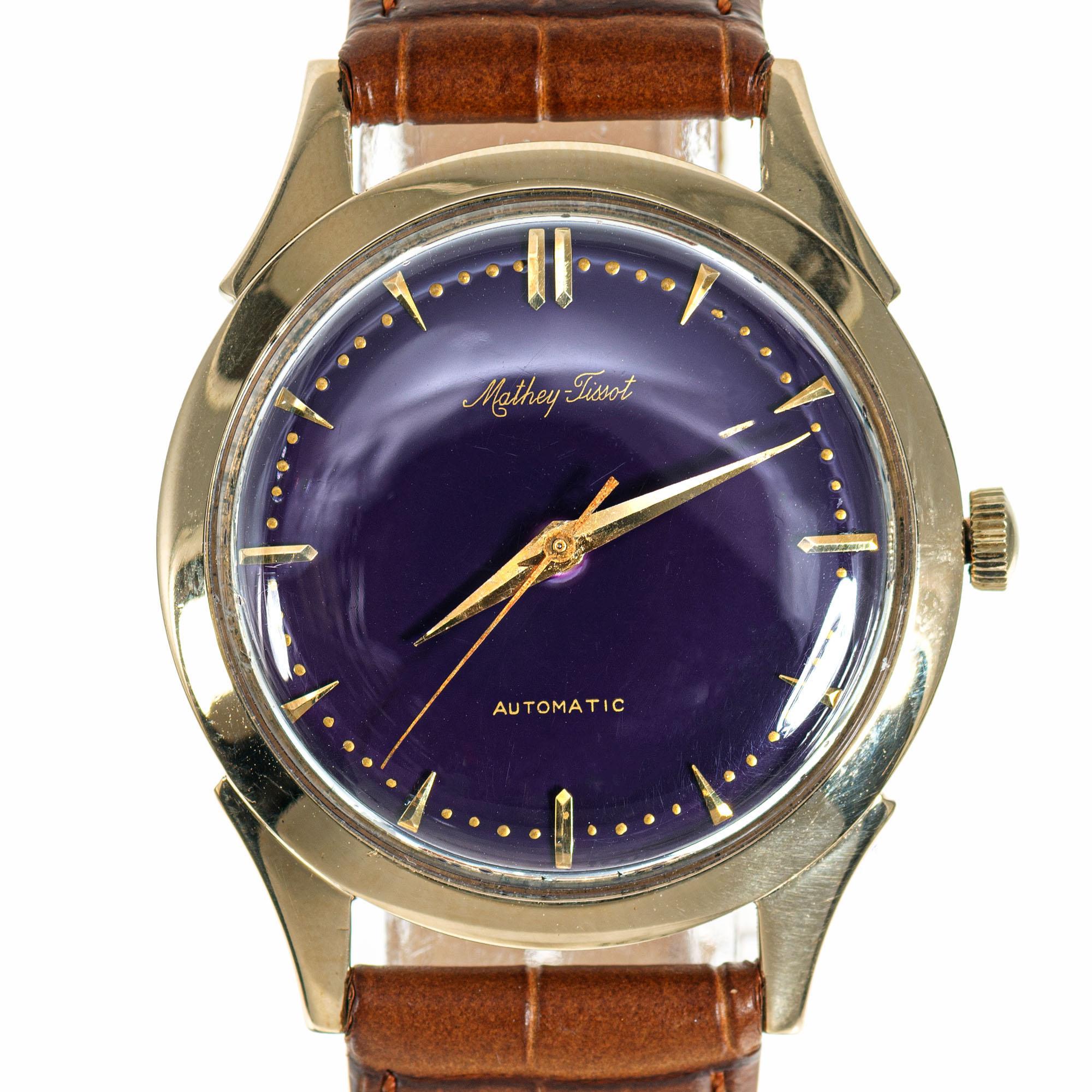 Mathey Tissot 14k yellow gold automatic wristwatch with custom-colored deep purple dial, circa 1960s. Brown leather band. 

14k yellow gold
Length: 42mm
Width: 34.54mm
Strap width at case: 18mm
Case thickness: 11mm
Dial: Custom-colored deep purple,