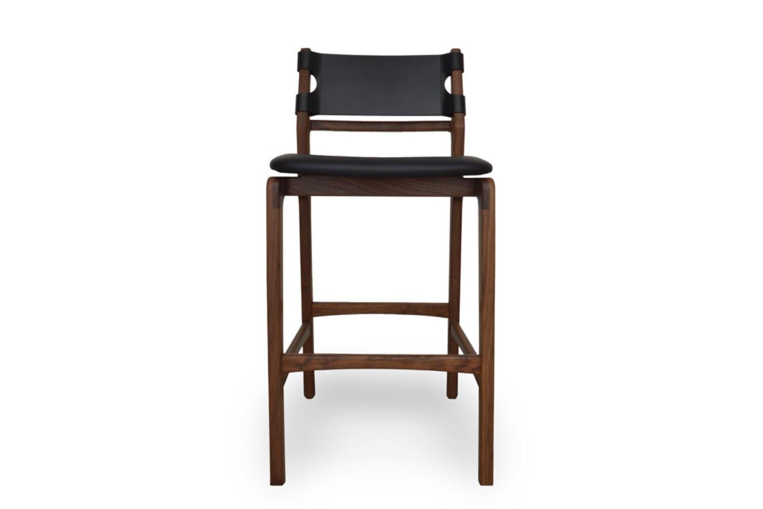 Taburete de bar de madera maciza con acabado al aceite, asiento tapizado en piel auténtica o tela a elegir, y respaldo de cuero duro. 
Disponible como taburete de bar o taburete de mostrador.
Esta pieza forma parte de la Sexta Colección de mob