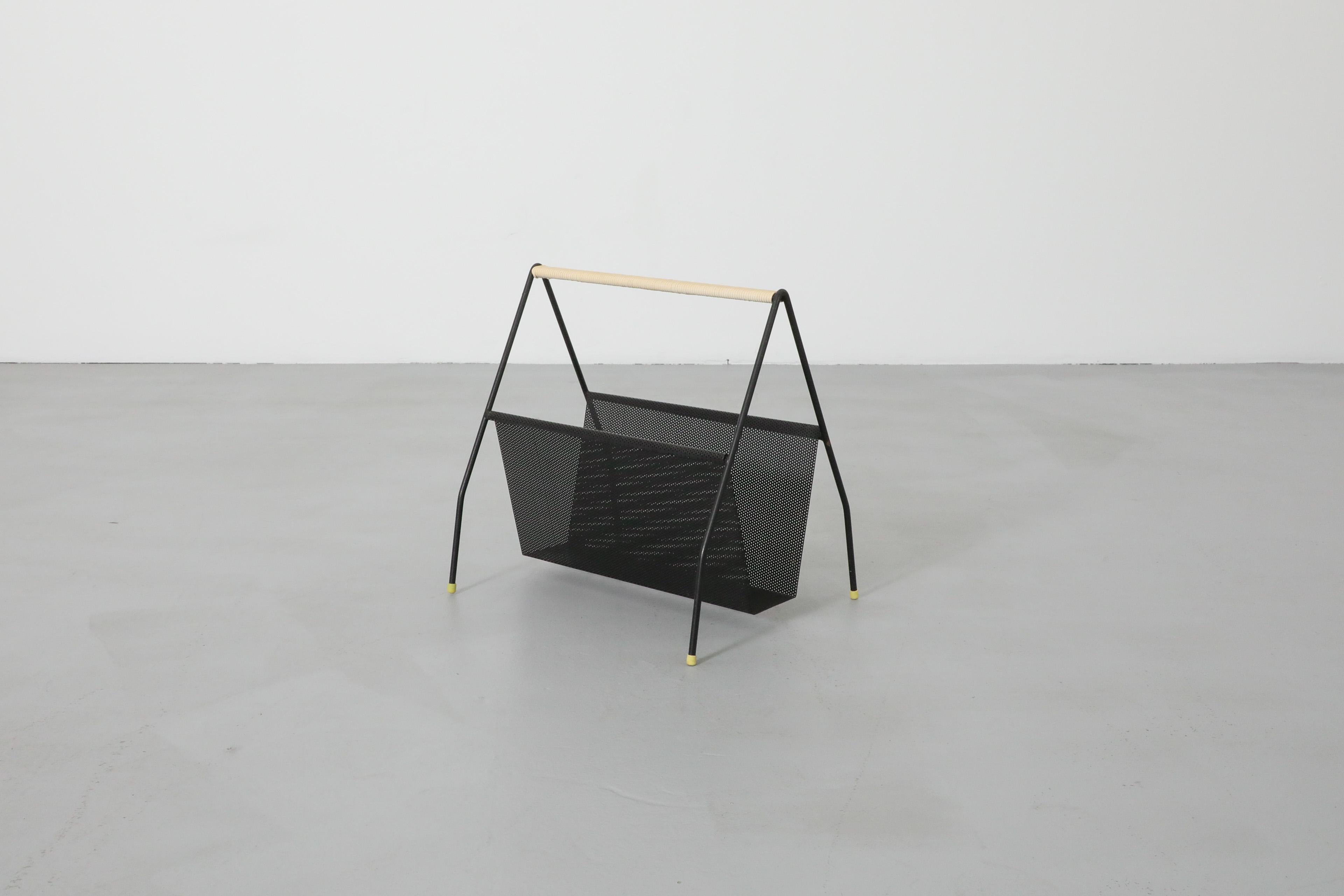Mid-Century Artimeta magazine rack with black enameled frame and perforated basket attributed to Mathieu Mategot. This stunningly simple designed magazine holder has a simple 