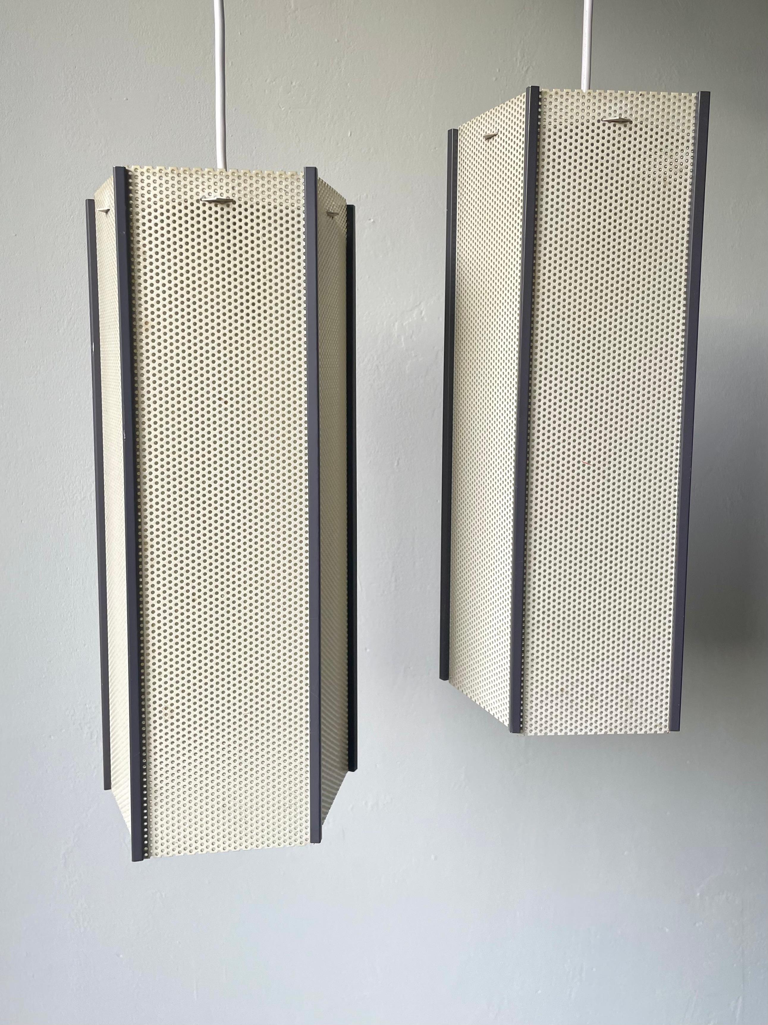 Set of two angular perforated metal pendants attributed to French-Hungarian designer Mathieu Matégot (1910-2001) in the 1950s. Five rectangular cream yellow metal sheets with a slight greenish tint creating a tall pentagon shape with slender gray