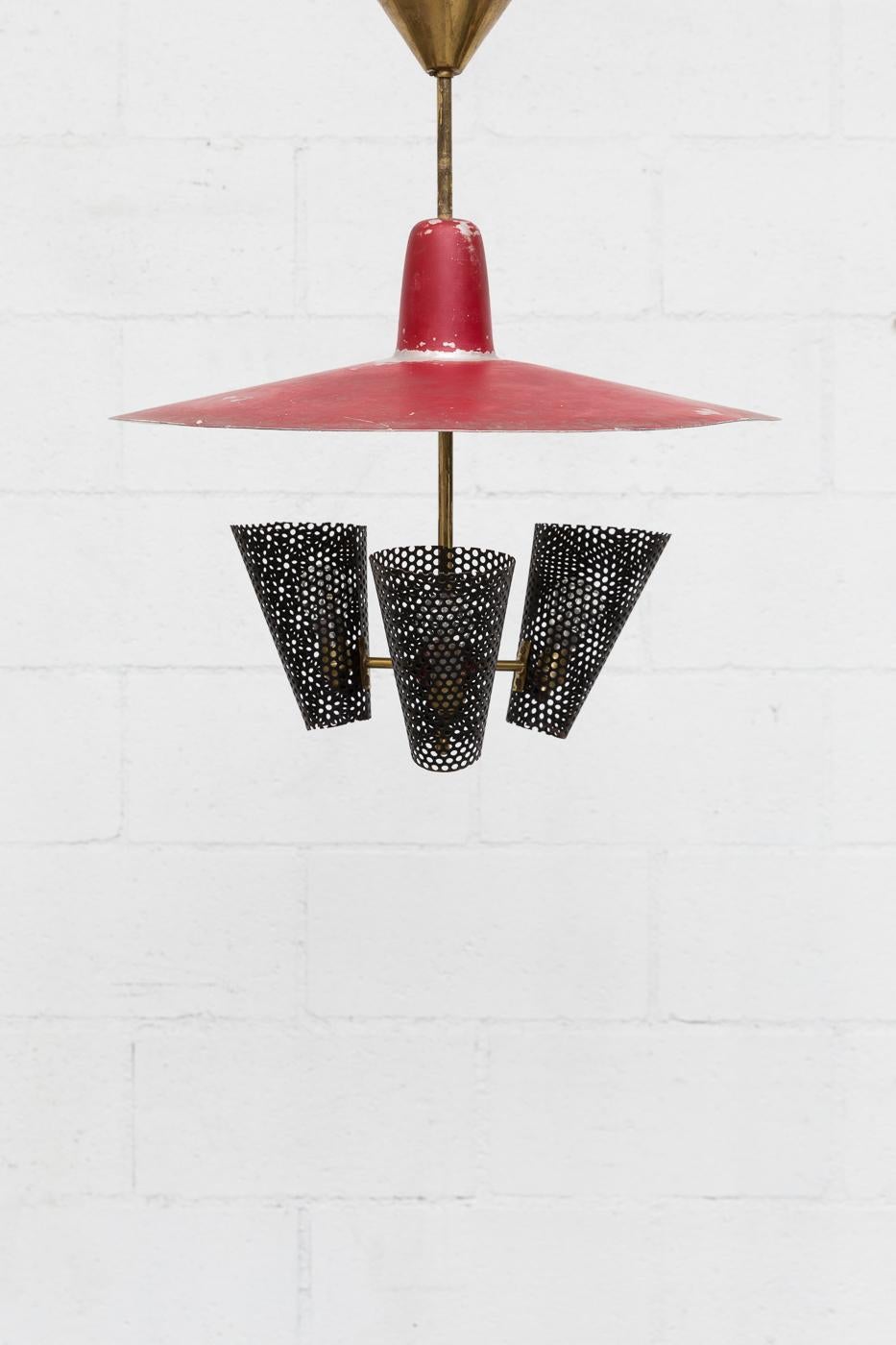 Handsome original enameled metal chandelier with three black enameled metal perforated cone shades, a red enameled metal top shade and brass hardware. In very original condition with heavy patina, showing visible wear and use.