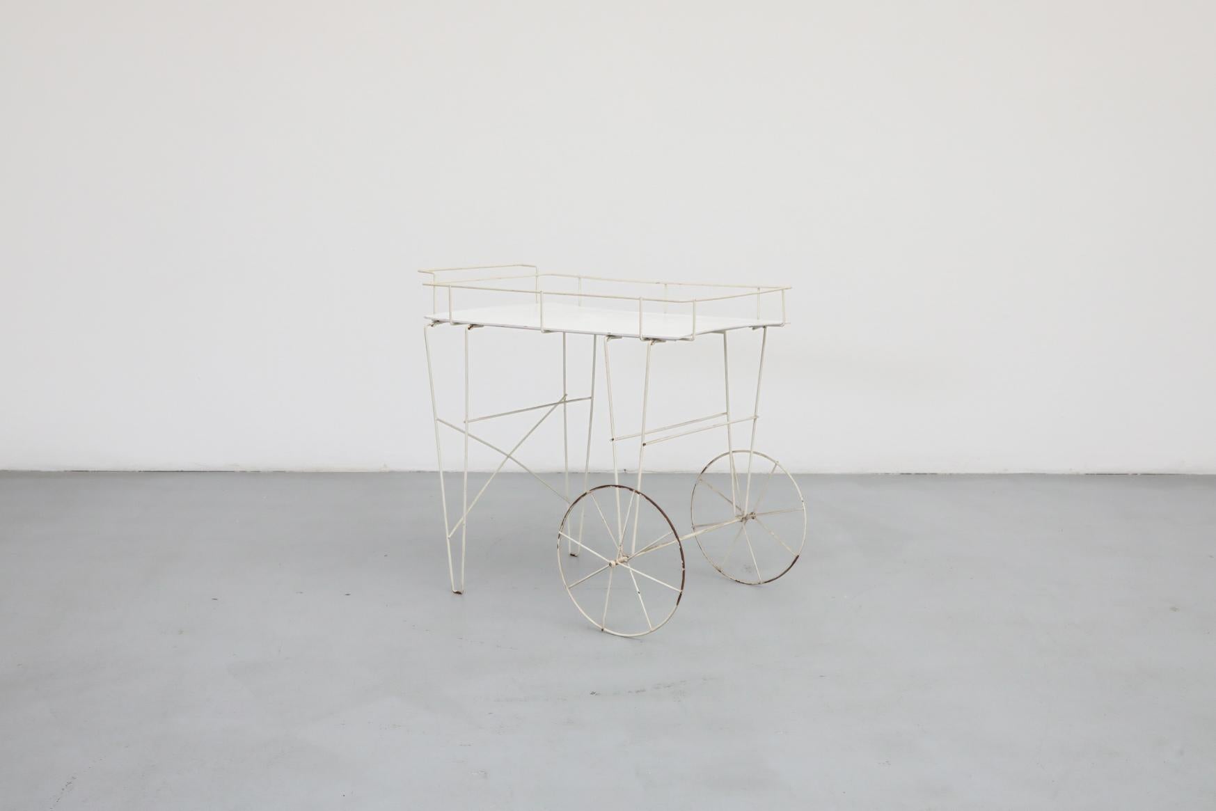 Mathieu Mategot inspired white enameled metal wire framed rolling flower cart with painted plywood tray. Very delicate wire frame, almost as though it is just a silhouette. In original condition with visible wear, including enamel loss, consistent