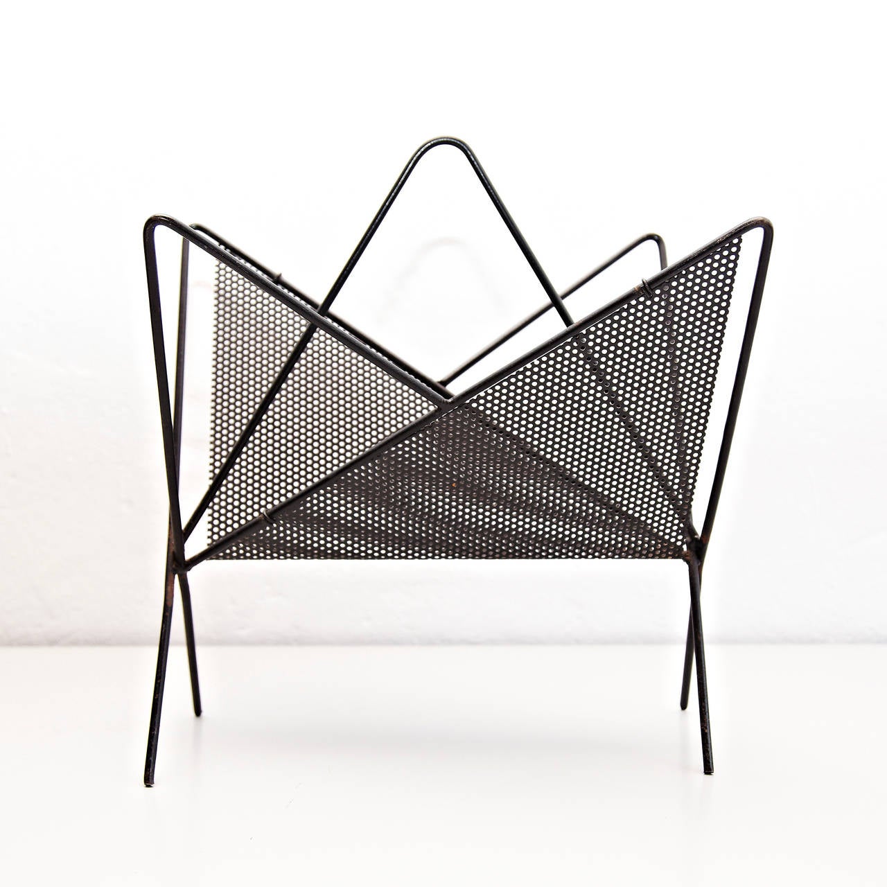 Magazine holder designed by Mathieu Matégot.
Manufactured by Ateliers Matégot (France), circa 1950.
Folded, perforated metal.

In good original condition, with minor wear consistent with age and use, preserving a beautiful patina.

Mathieu