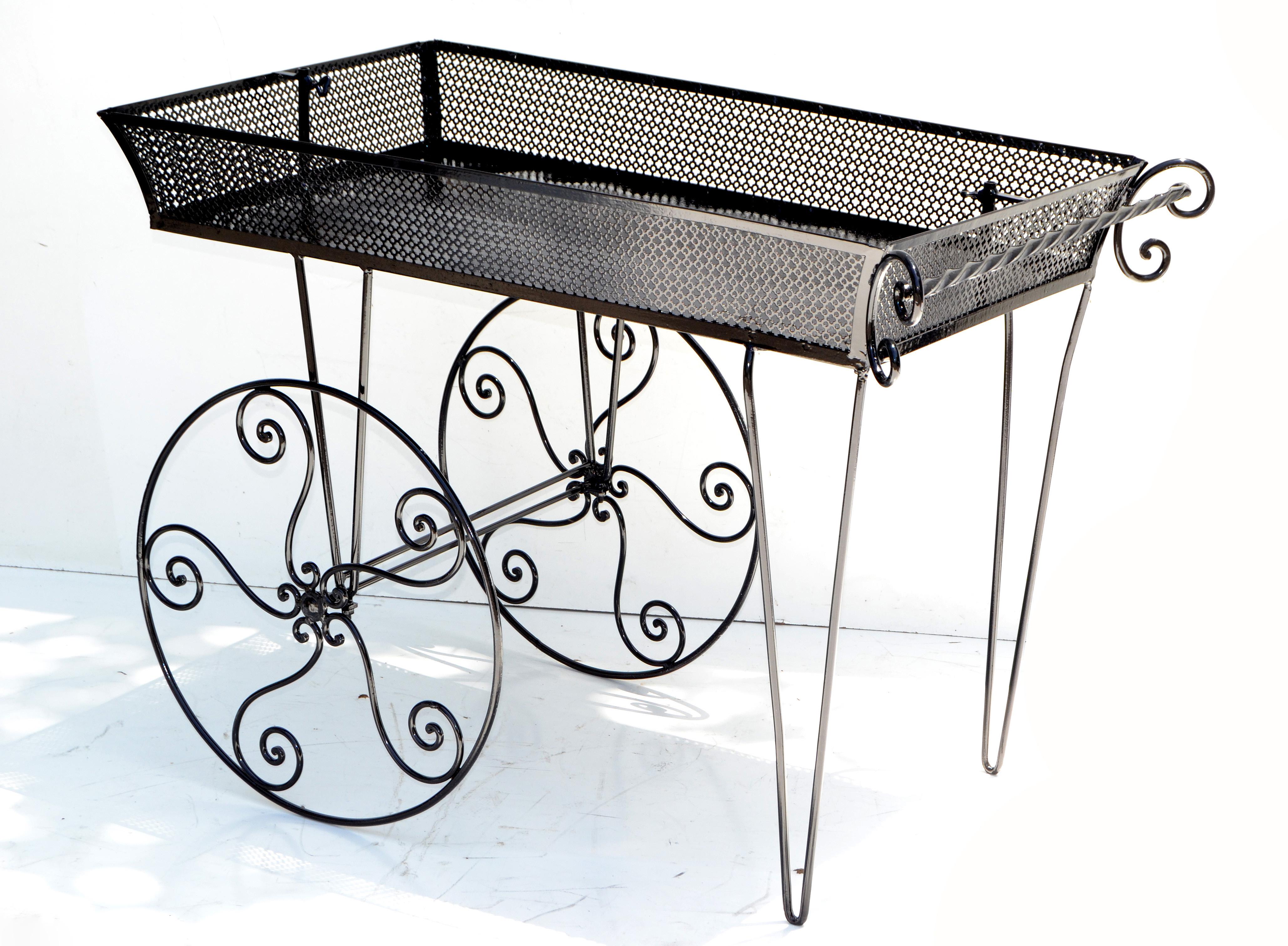 Superb Mid-Century Modern paris marketplace flower cart in the style of Mathieu Matégot.
Handcrafted wrought iron wheels, hairpin legs, handles and a metal mesh display table in gloss black finish.
Iconic paris marketplace collector's item.
  